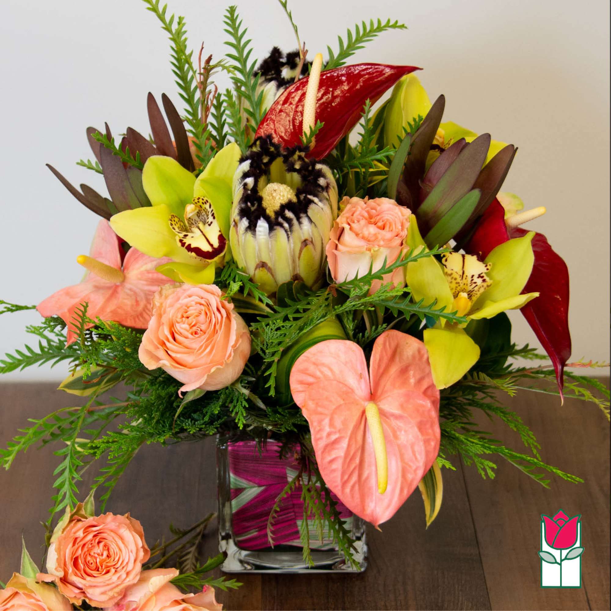 Bouquet of orchids, roses, and anthuriums in a square glass vase
