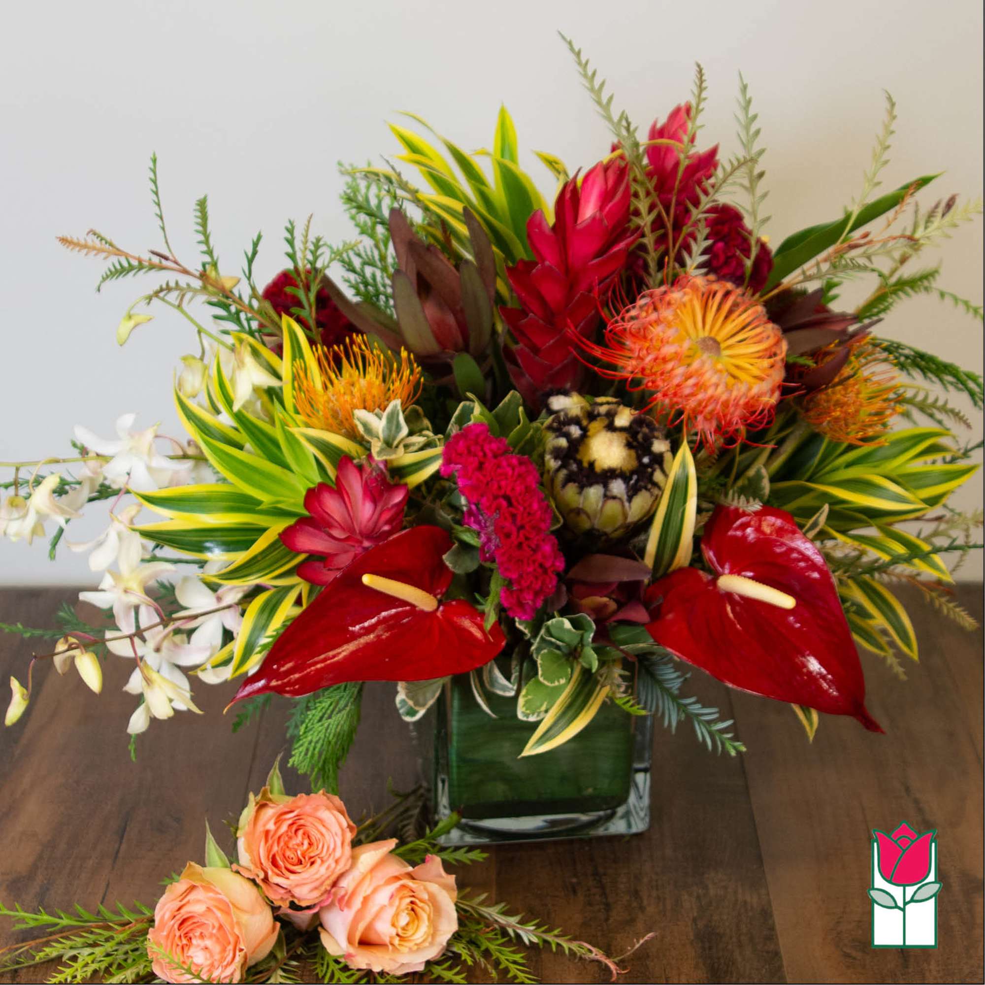 Tropical bouquet with red anthuriums and orange protea in a glass vase