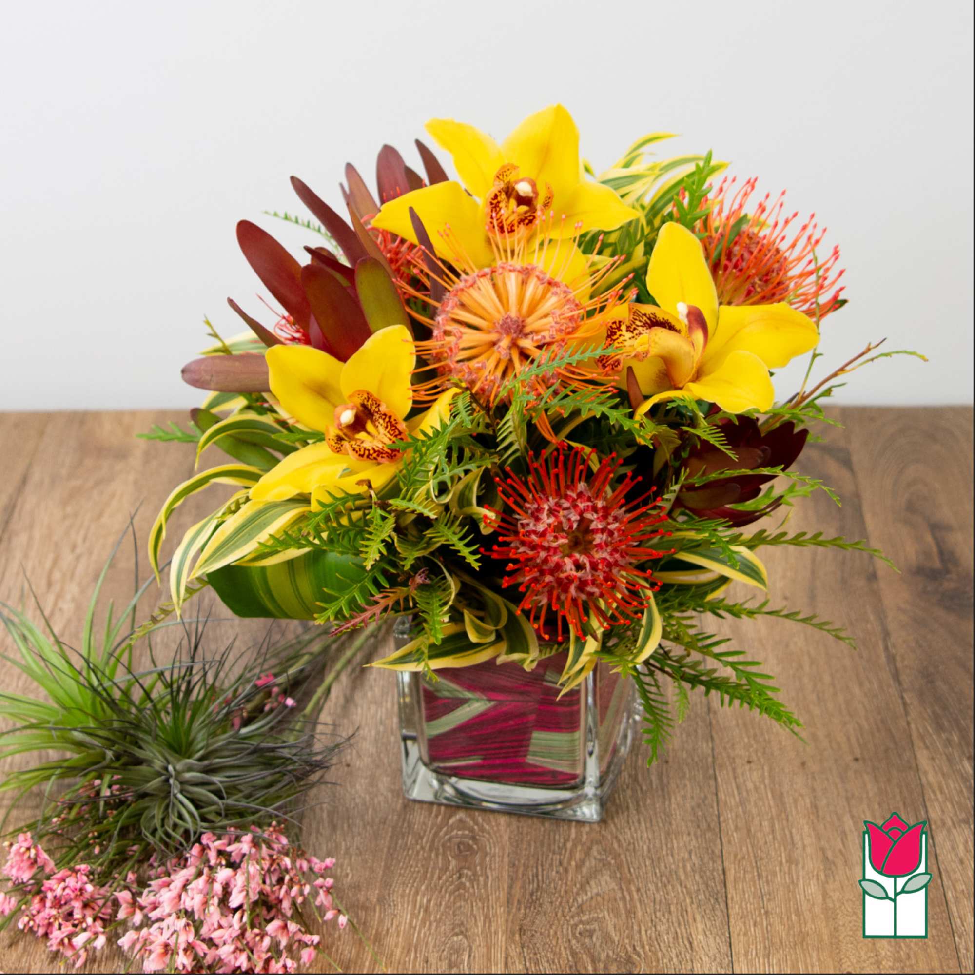 Yellow orchids and red tropical flowers in a glass vase