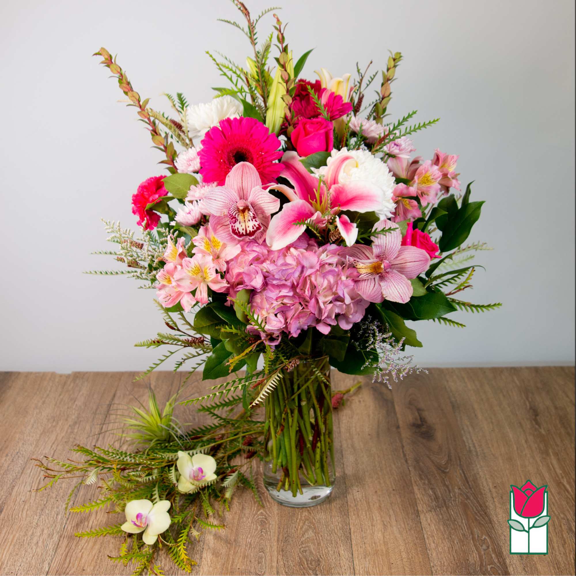 Pink and white mixed bouquet in a clear glass vase with orchids and roses