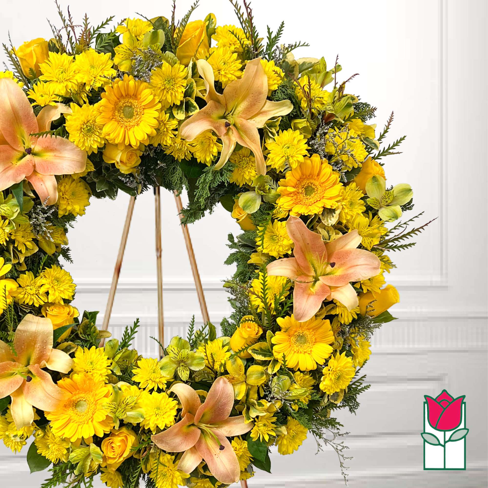 Yellow floral wreath with peach lilies on a stand