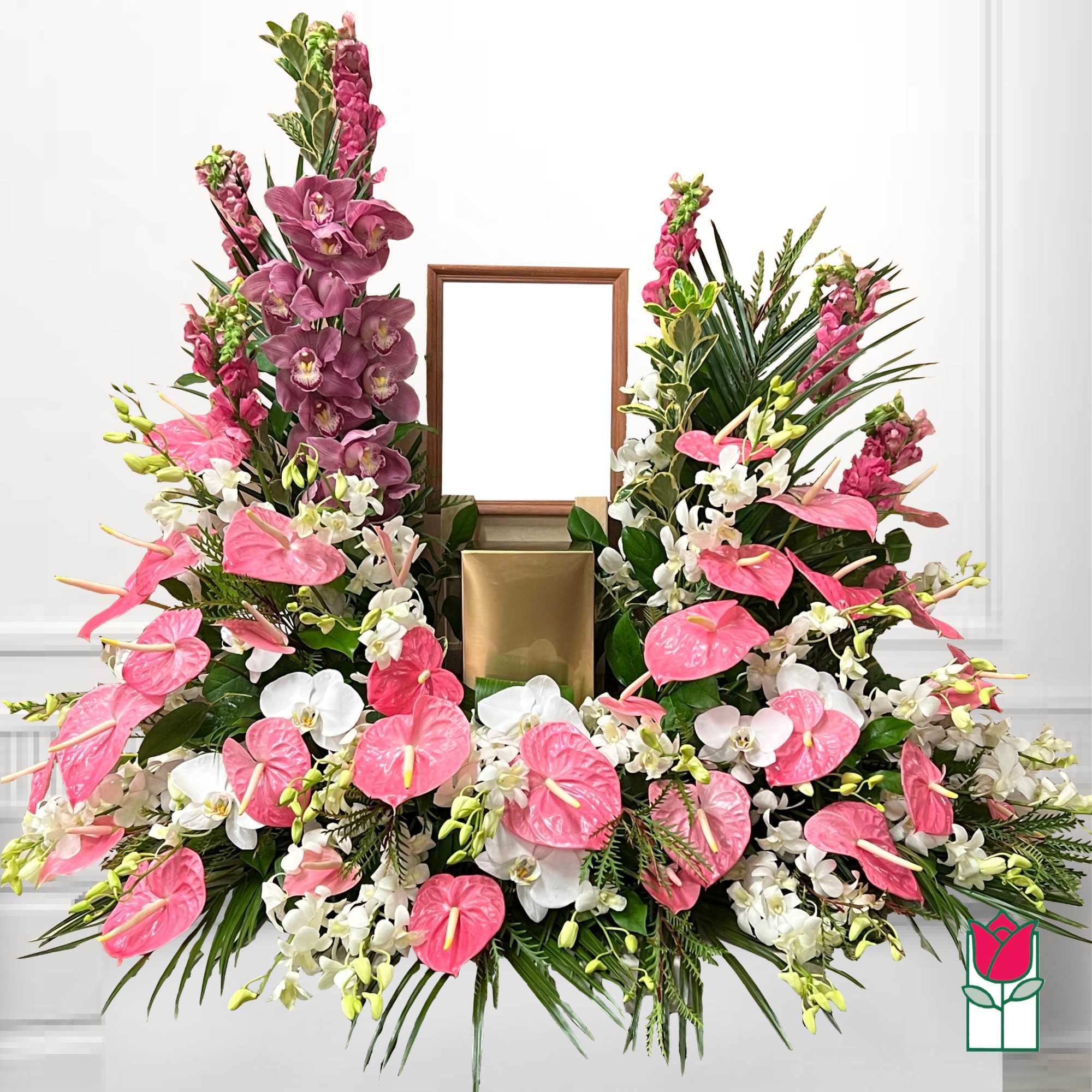 Pink and white floral funeral spray with a framed center and gold urn