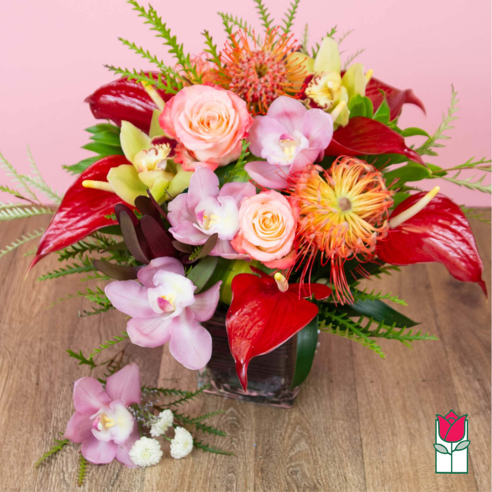 Bouquet of pink roses, orchids, and red tropical flowers in a glass vase