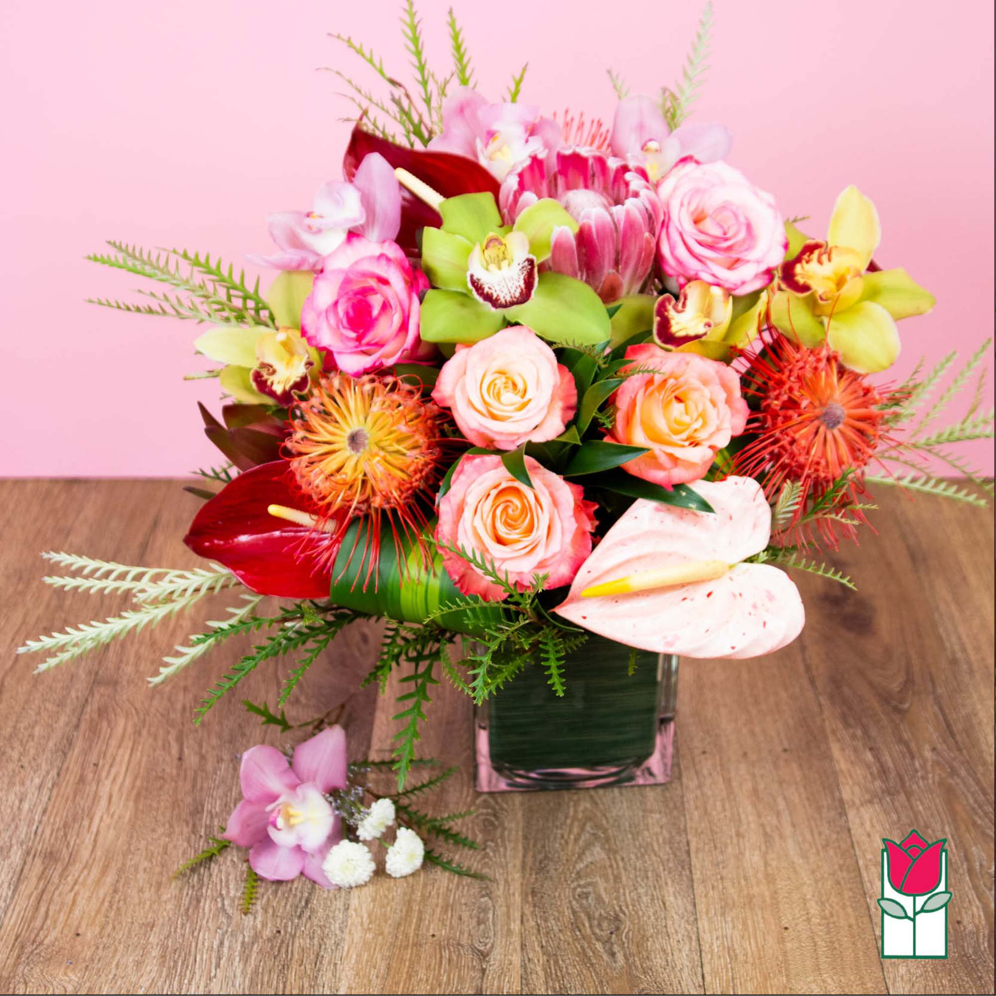 Mixed pink and peach floral arrangement in a square glass vase