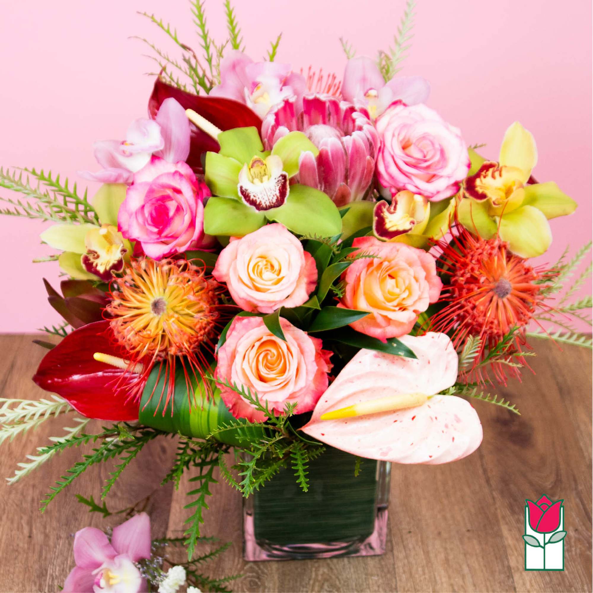 Mixed bouquet in a square glass vase with pink and peach blooms