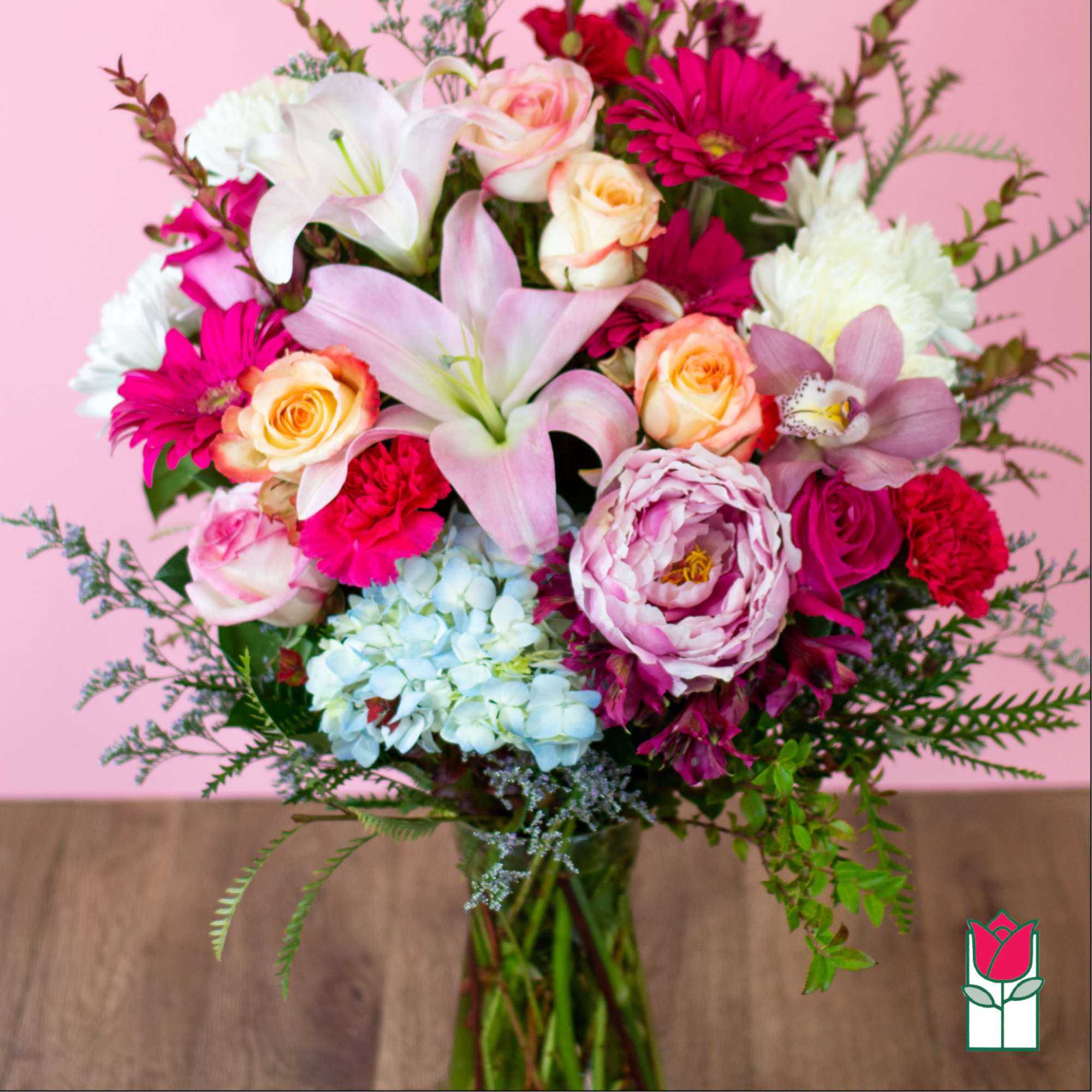 Mixed bouquet with pink lilies, roses, and daisies in a glass vase