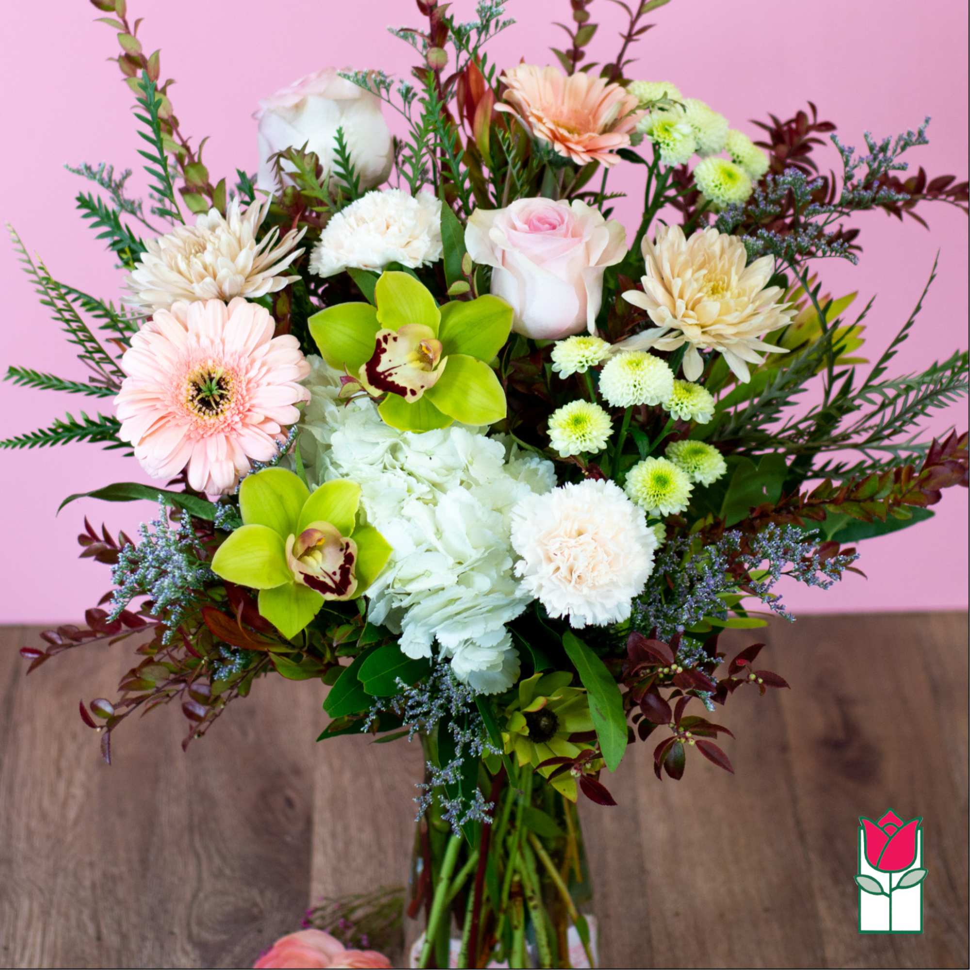 Mixed bouquet with pink, white, and green flowers in a glass vase