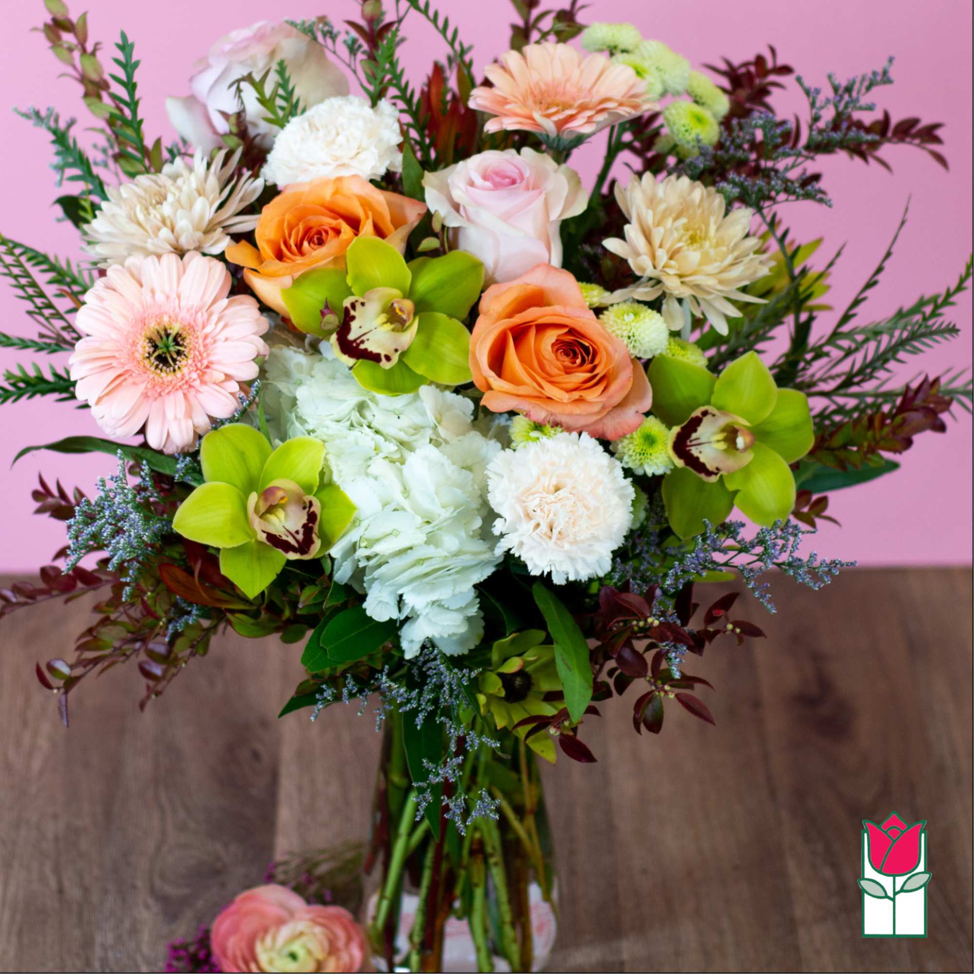 Mixed bouquet of roses, orchids, and daisies in a glass vase