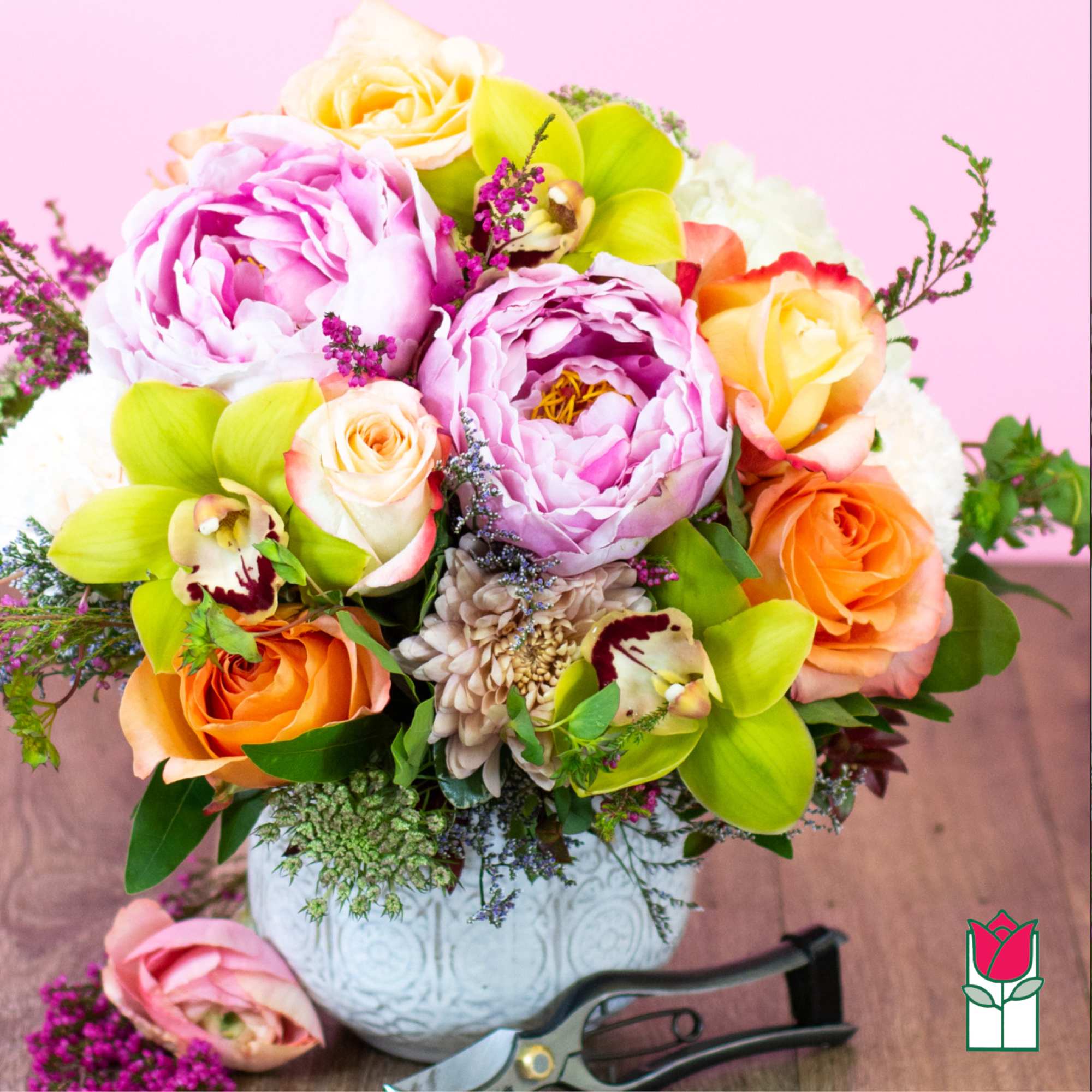 Bouquet of pink peonies, roses, and orchids in a white vase