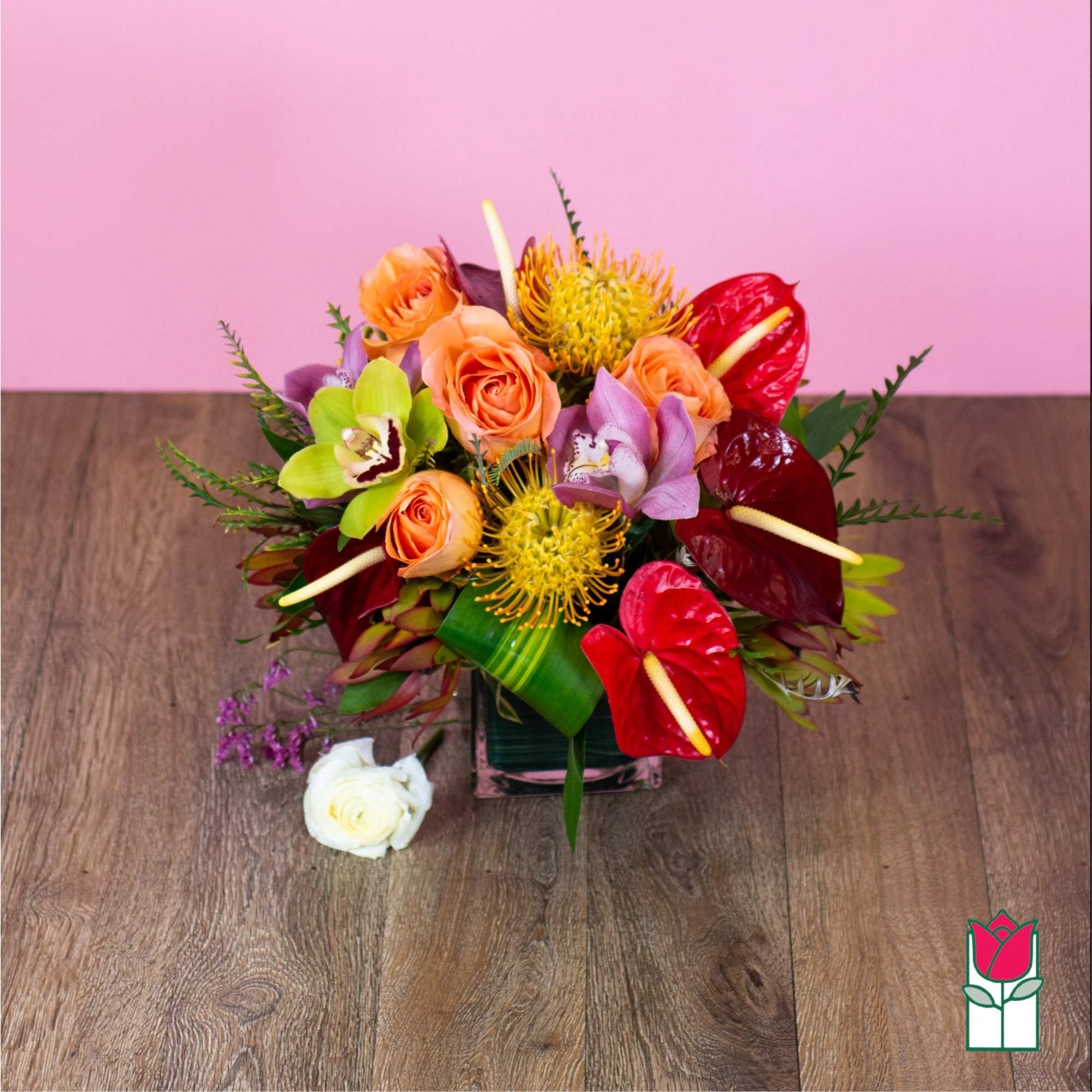 Colorful bouquet with roses, orchids, and anthuriums in a glass vase
