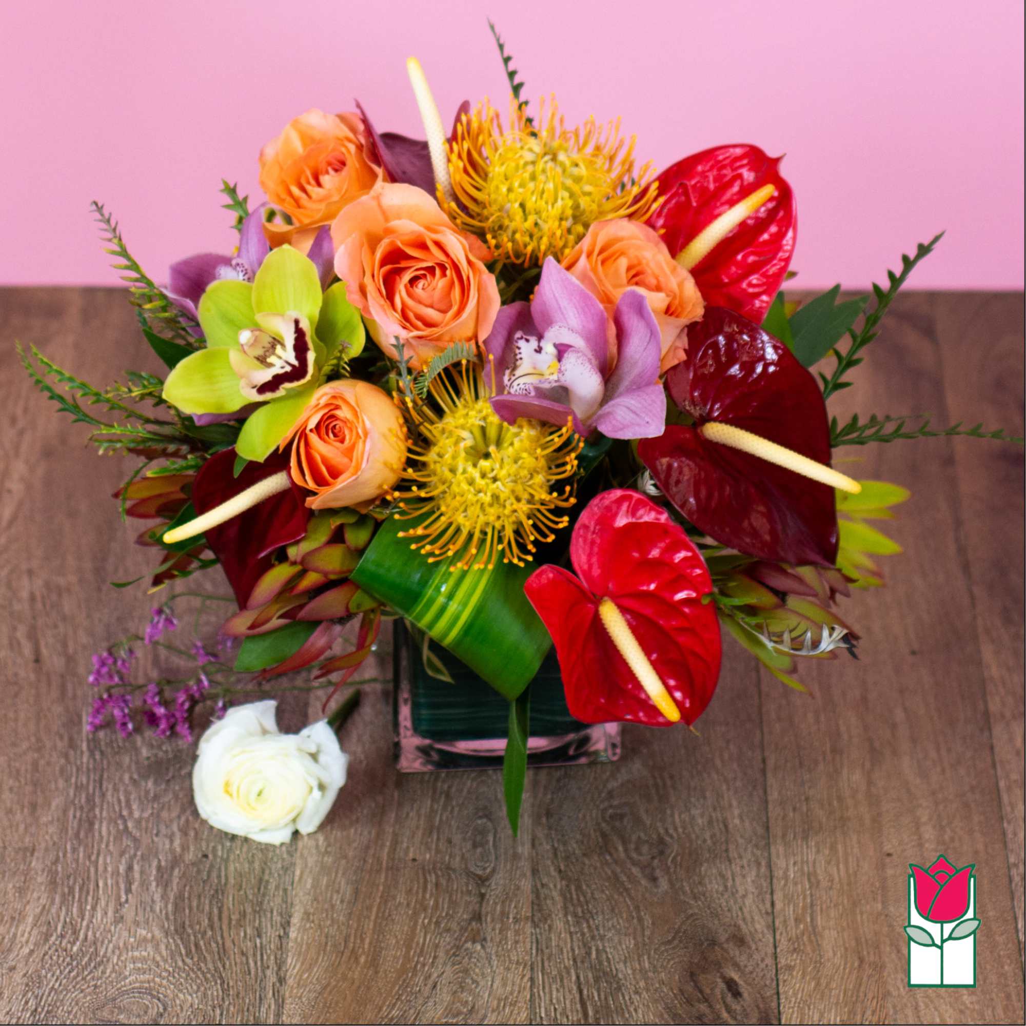 Tropical bouquet with roses, orchids, and anthuriums in a glass vase
