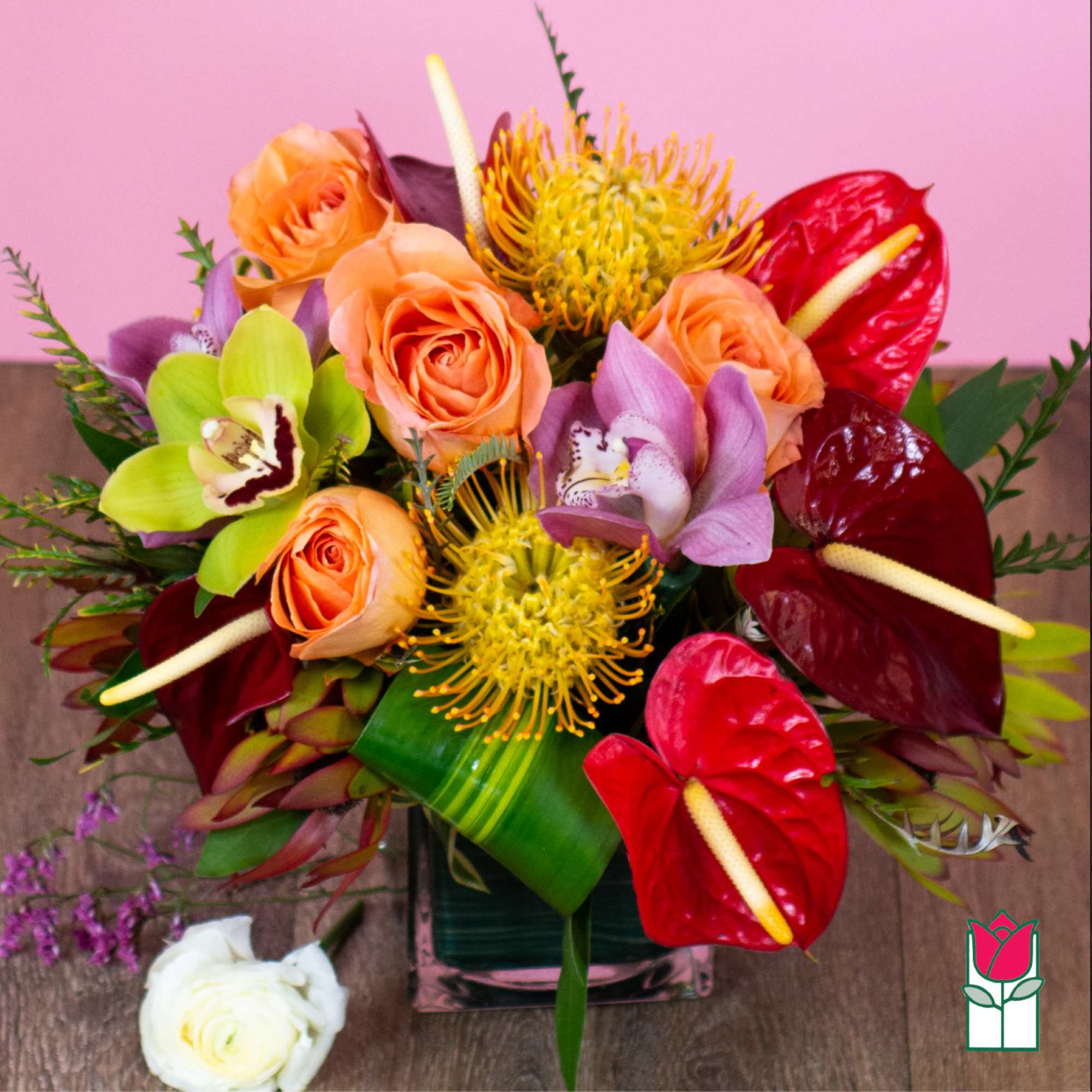Bouquet of orange roses, orchids, and red anthuriums in a glass vase