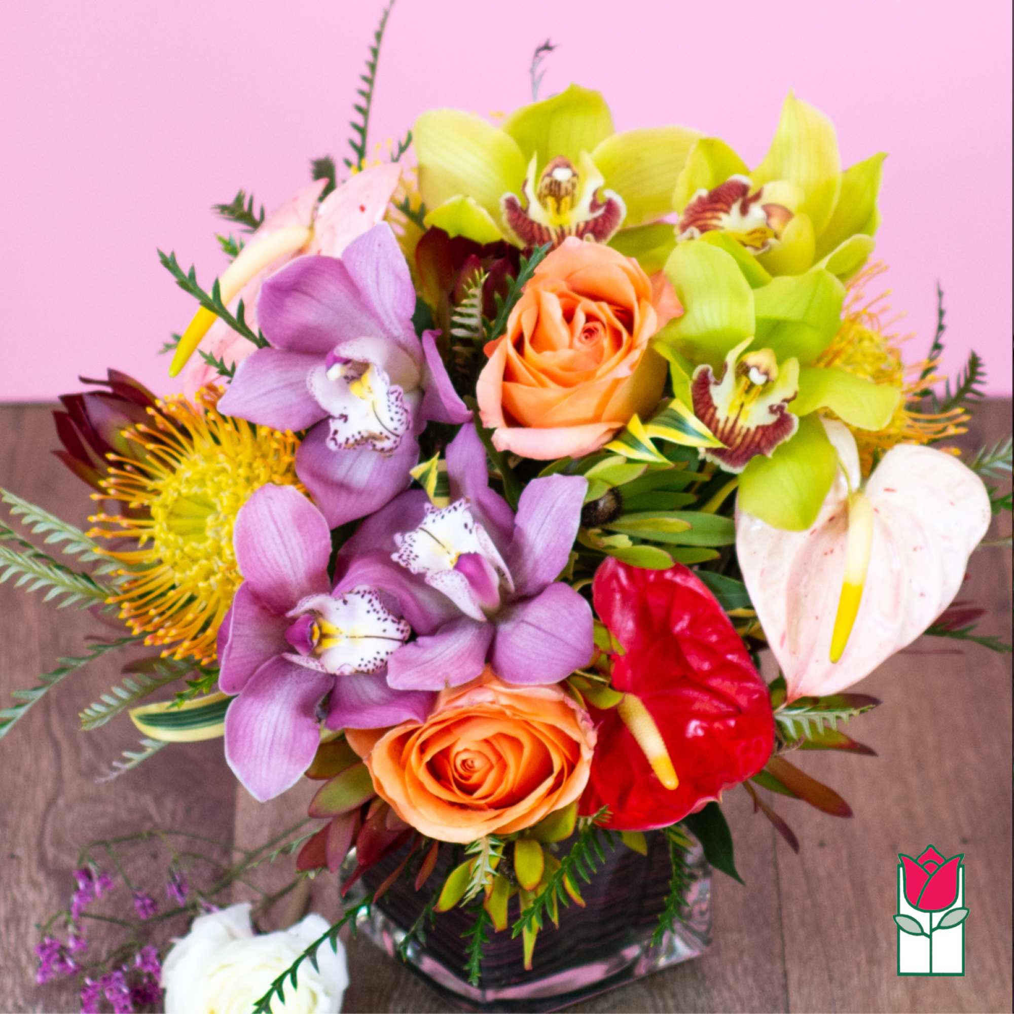 Mixed bouquet of orchids, roses, and anthuriums in a glass vase