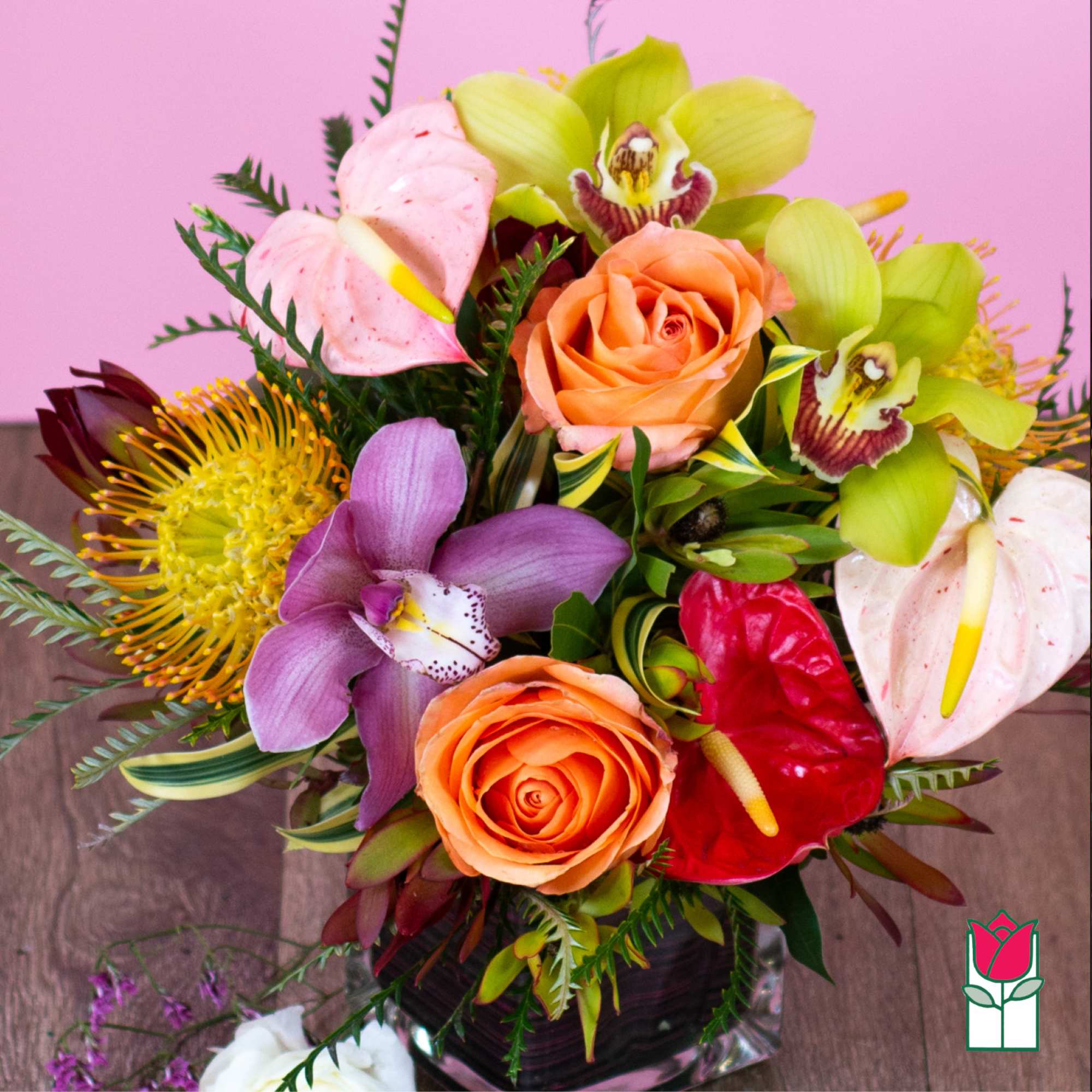 Colorful bouquet with roses, orchids, and anthuriums in a glass vase