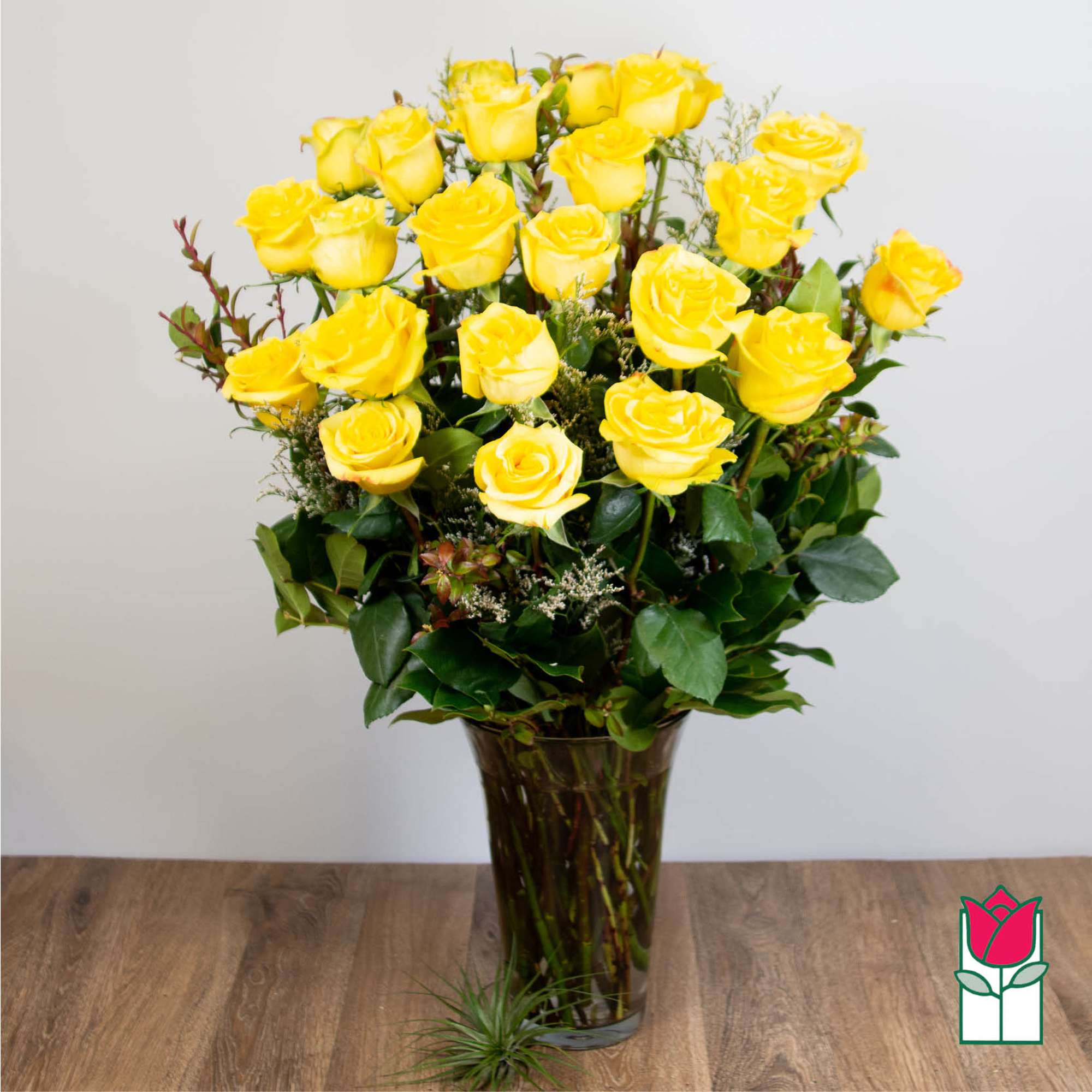 Yellow roses arranged in a tall glass vase