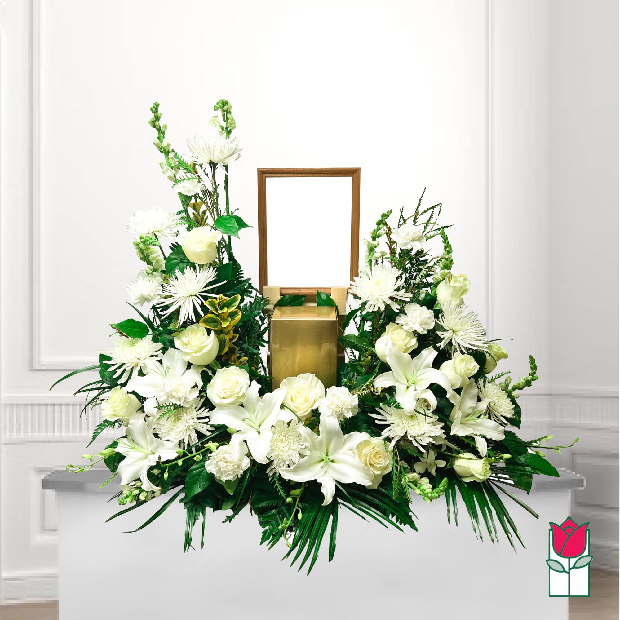 White floral funeral arrangement with a gold urn and wooden frame