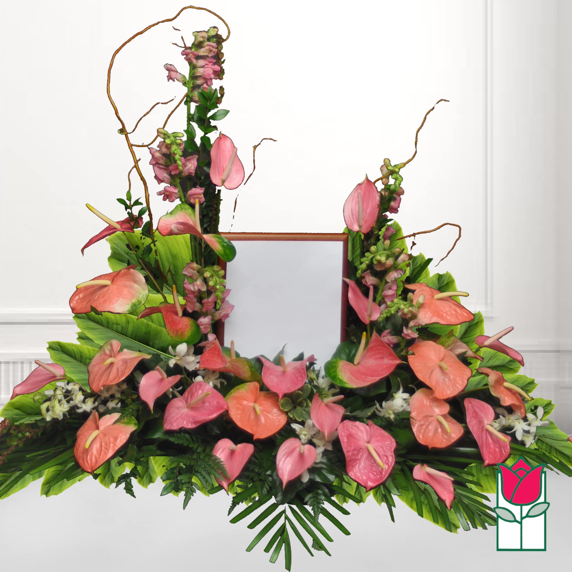 Pink anthuriums and white flowers arranged around a framed center piece