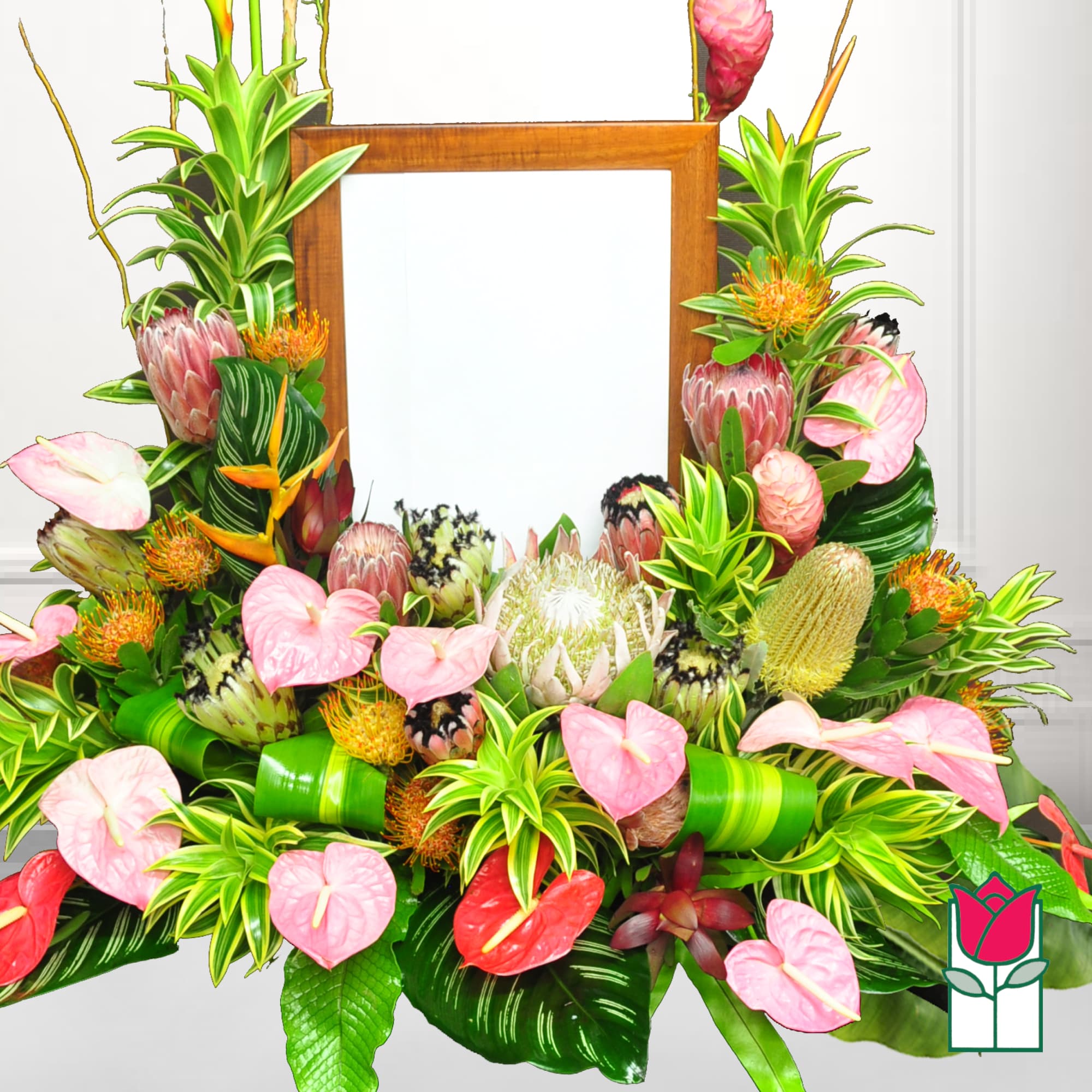Tropical floral arrangement with pink anthuriums and protea around a wooden frame, photo 2 of 2