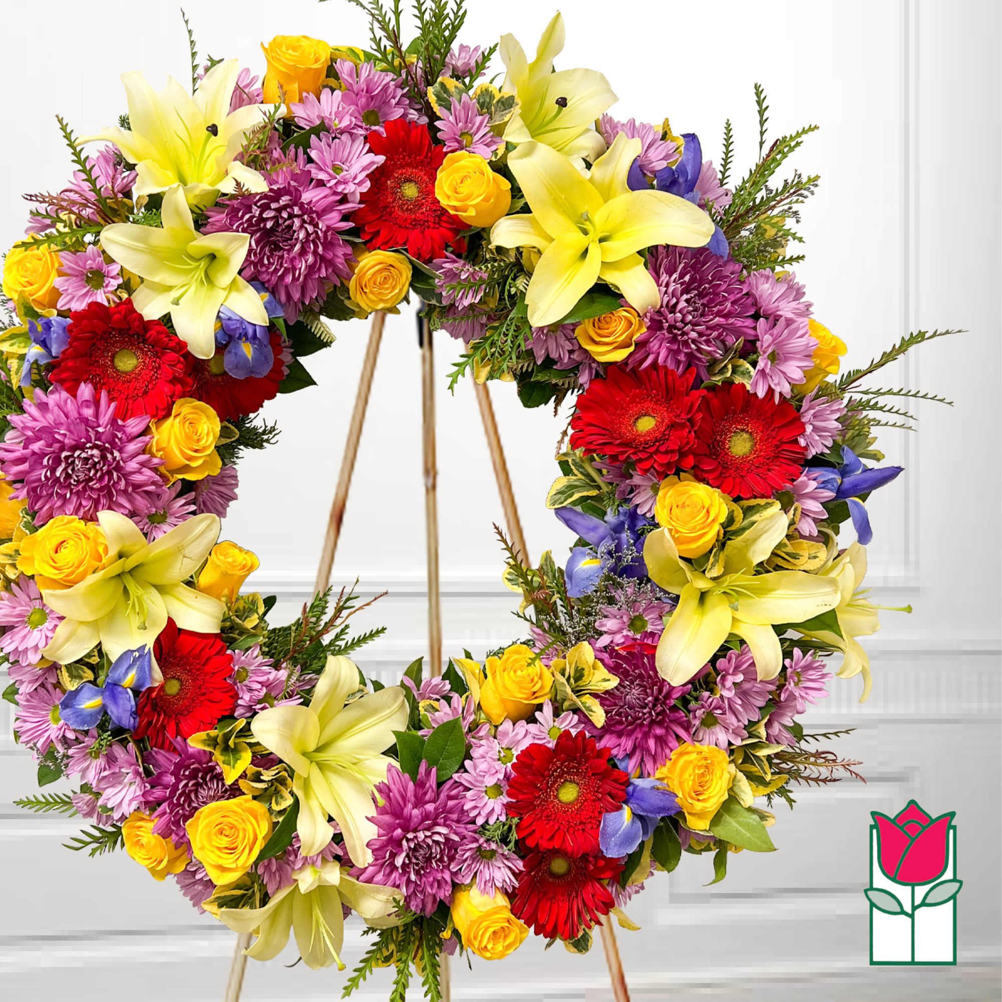 Heart-shaped floral wreath with lilies, roses, gerbera daisies, and purple mums