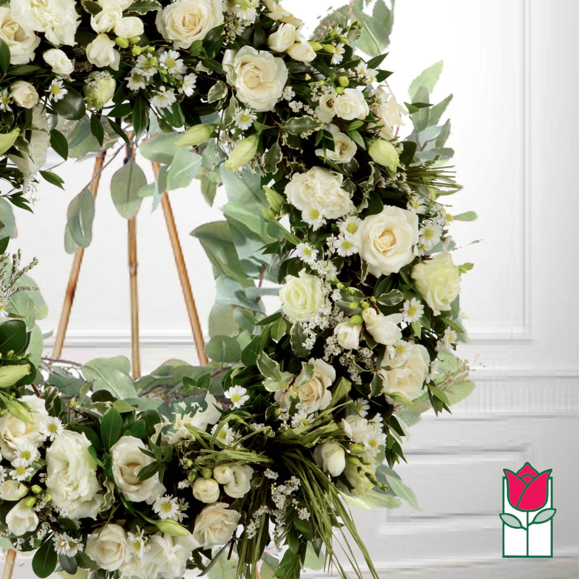 White rose floral wreath with greenery on a stand