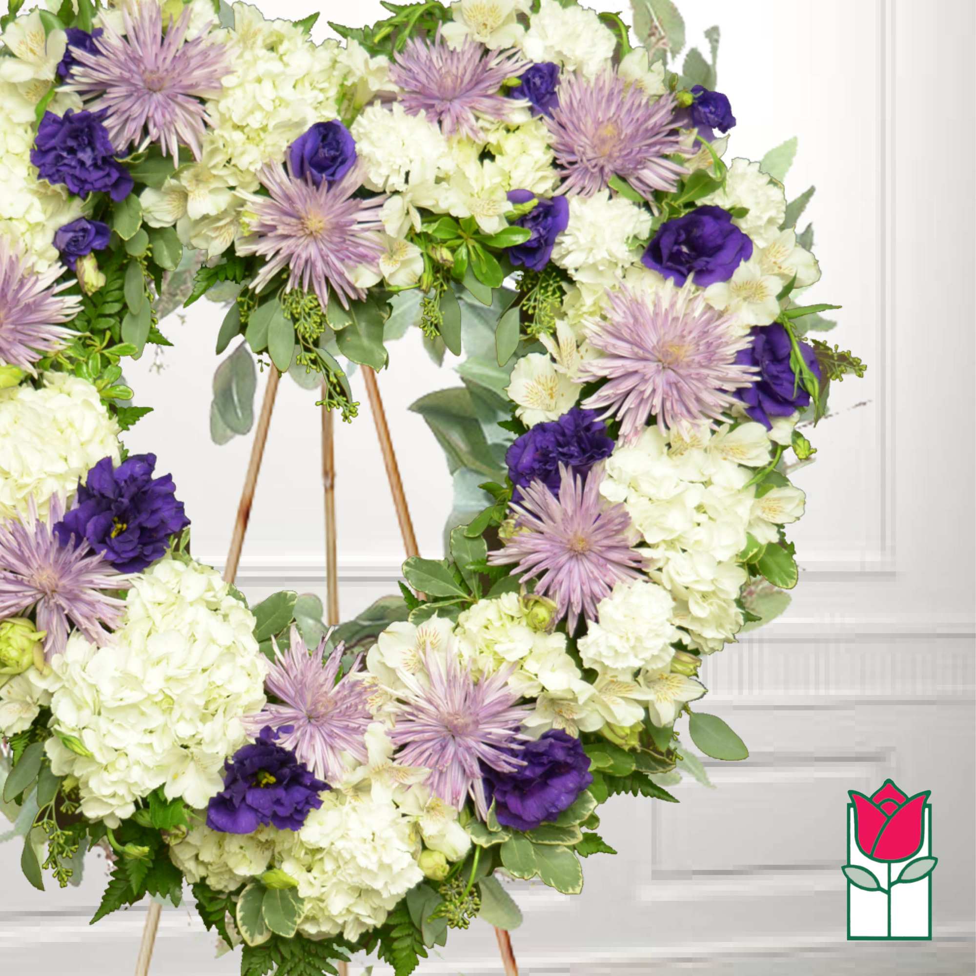 Heart-shaped floral wreath with white and purple flowers on a stand