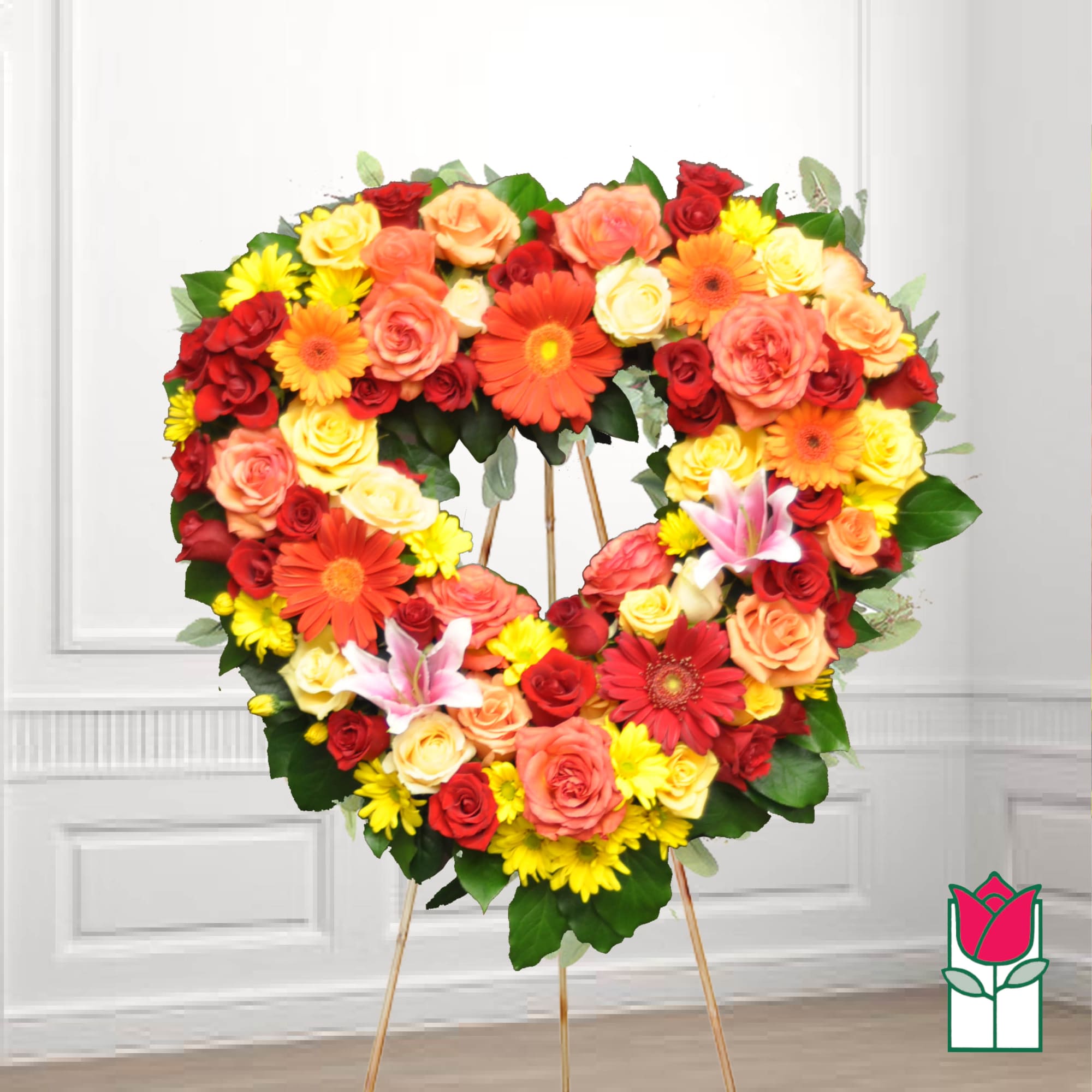 Heart-shaped floral wreath on an easel with roses, daisies, and lilies