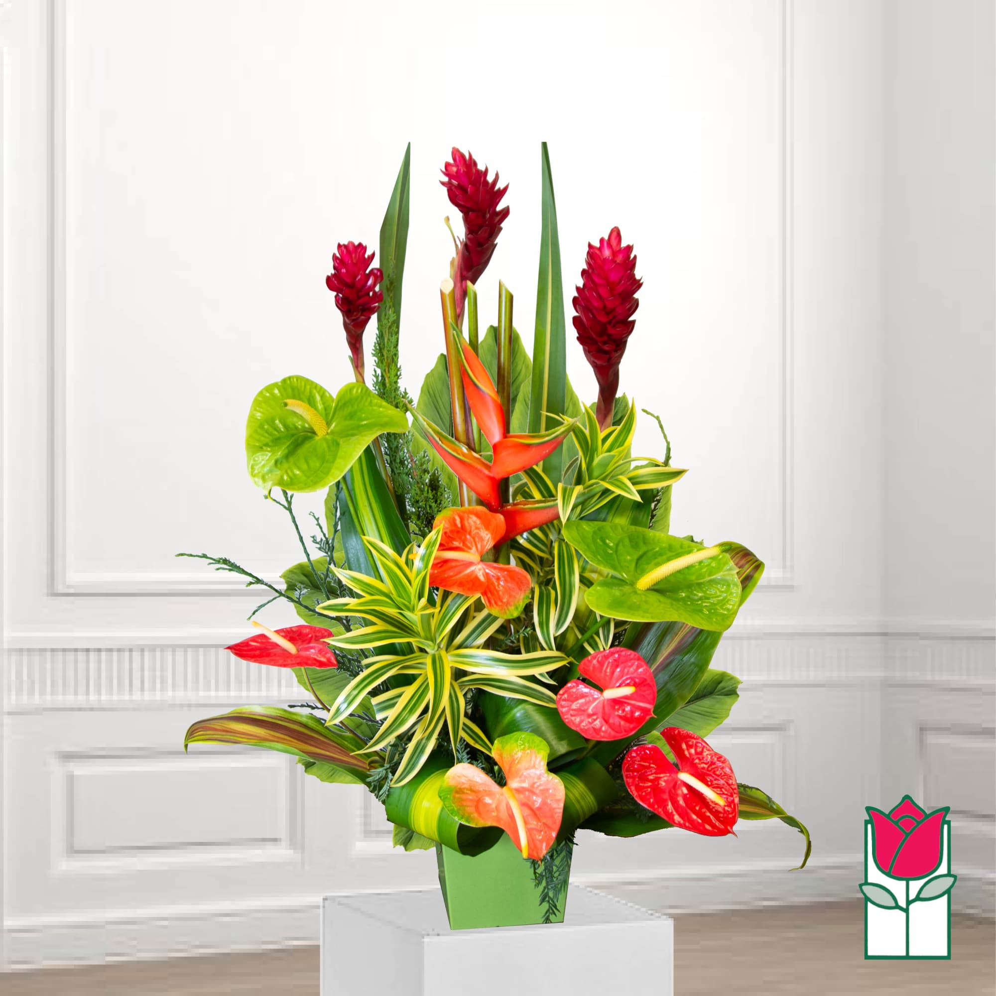 Tropical floral arrangement in a green vase with red and orange blooms