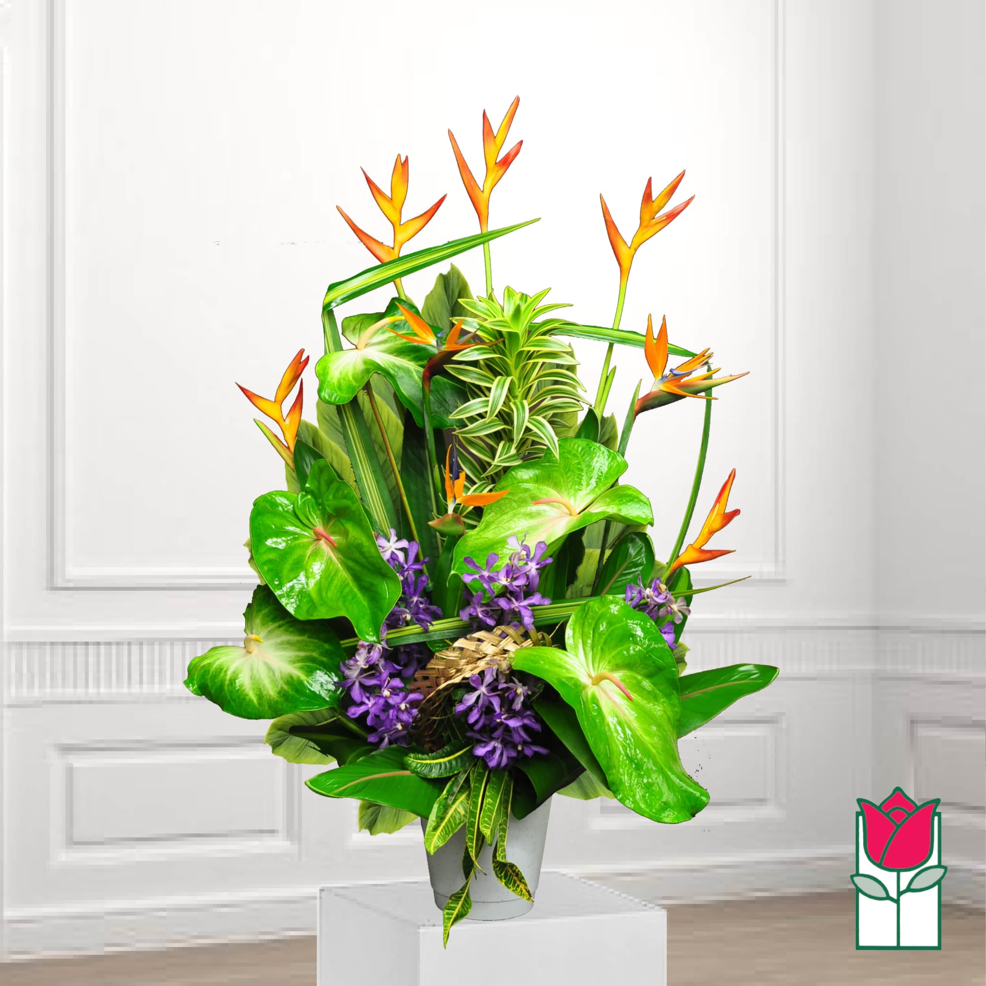 Tropical arrangement with orange bird-of-paradise and purple flowers in a white pot