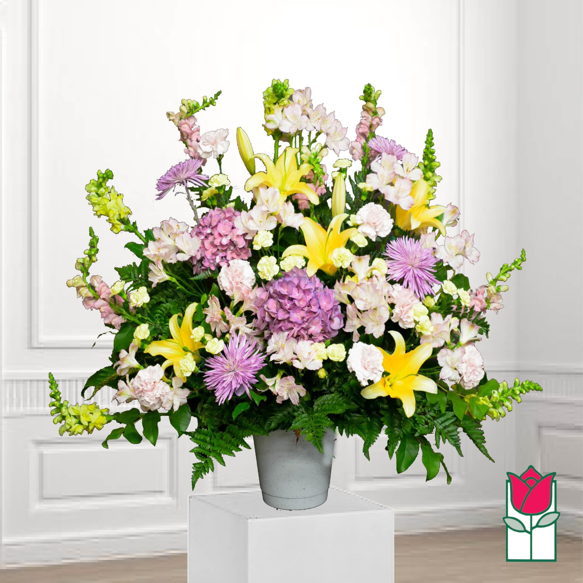 Large mixed flower arrangement in a gray vase with yellow lilies and pink blooms