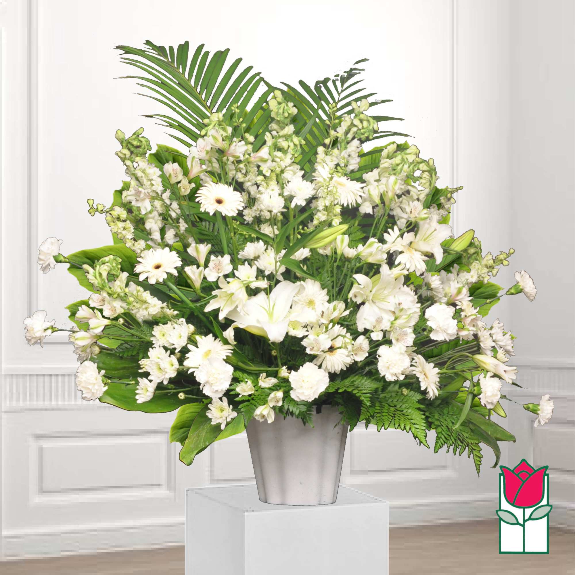 White floral arrangement in a silver vase with green foliage