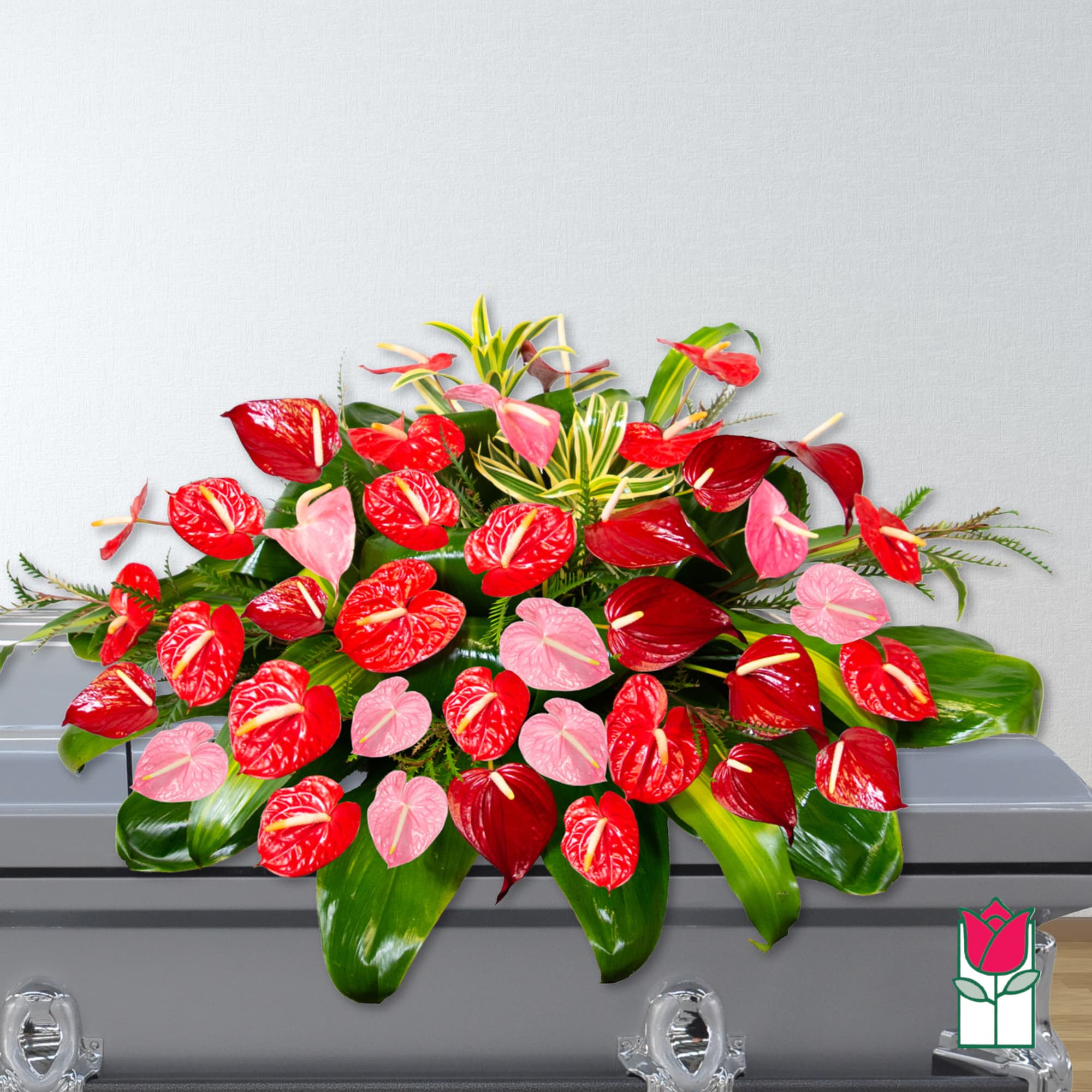 Red and pink anthurium arrangement on a casket