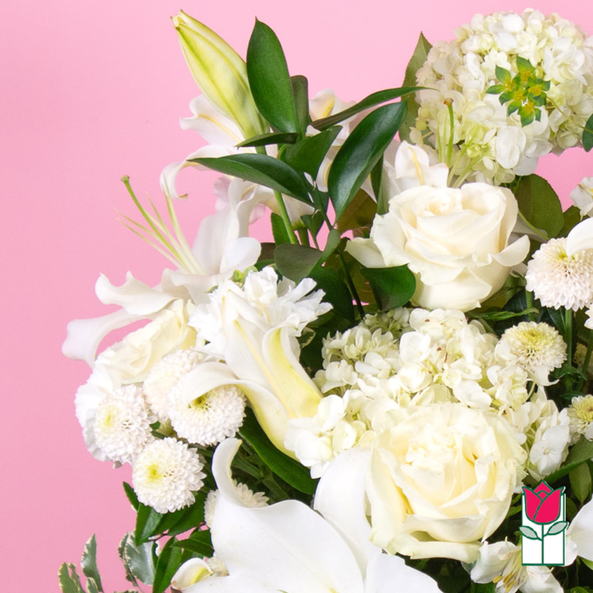 White roses, lilies, and hydrangeas in a bouquet against a pink background