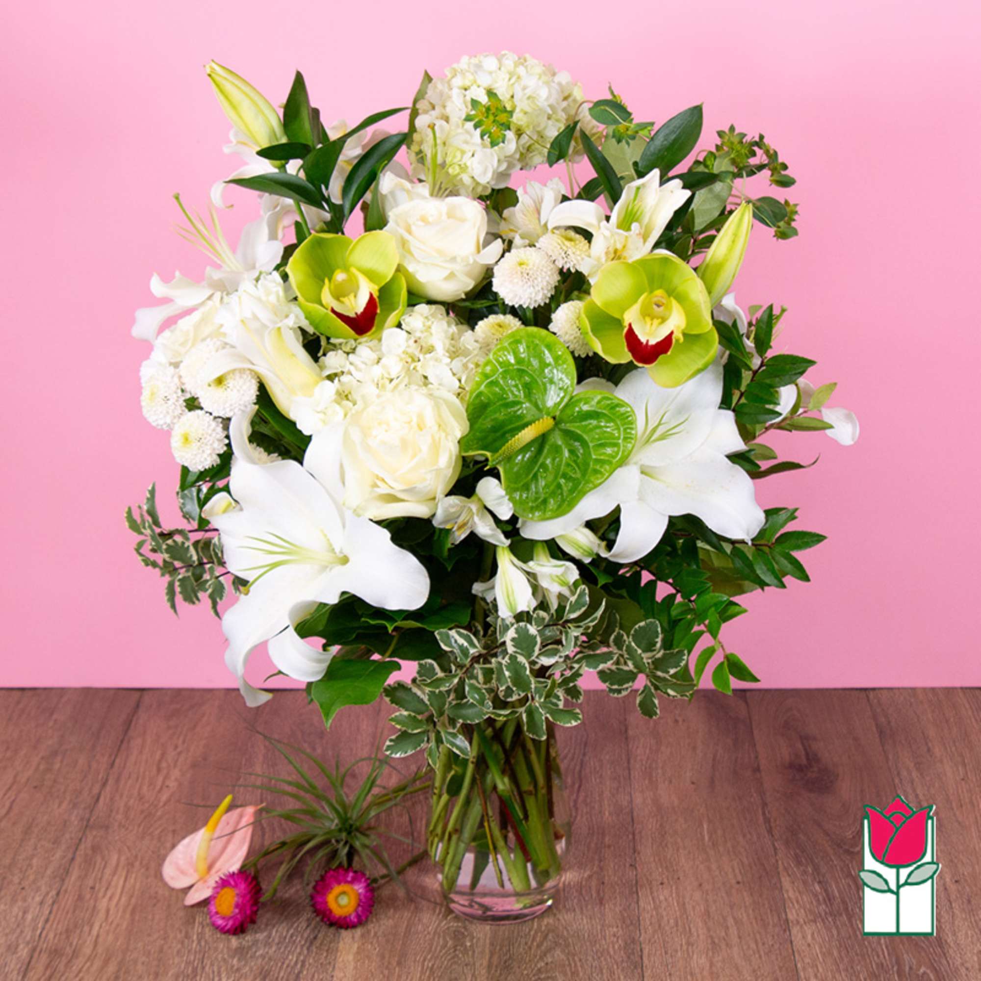White lilies and orchids arranged in a clear glass vase