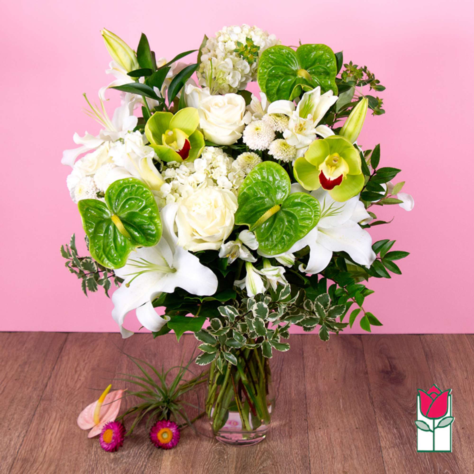 White lilies and roses with green orchids in a glass vase