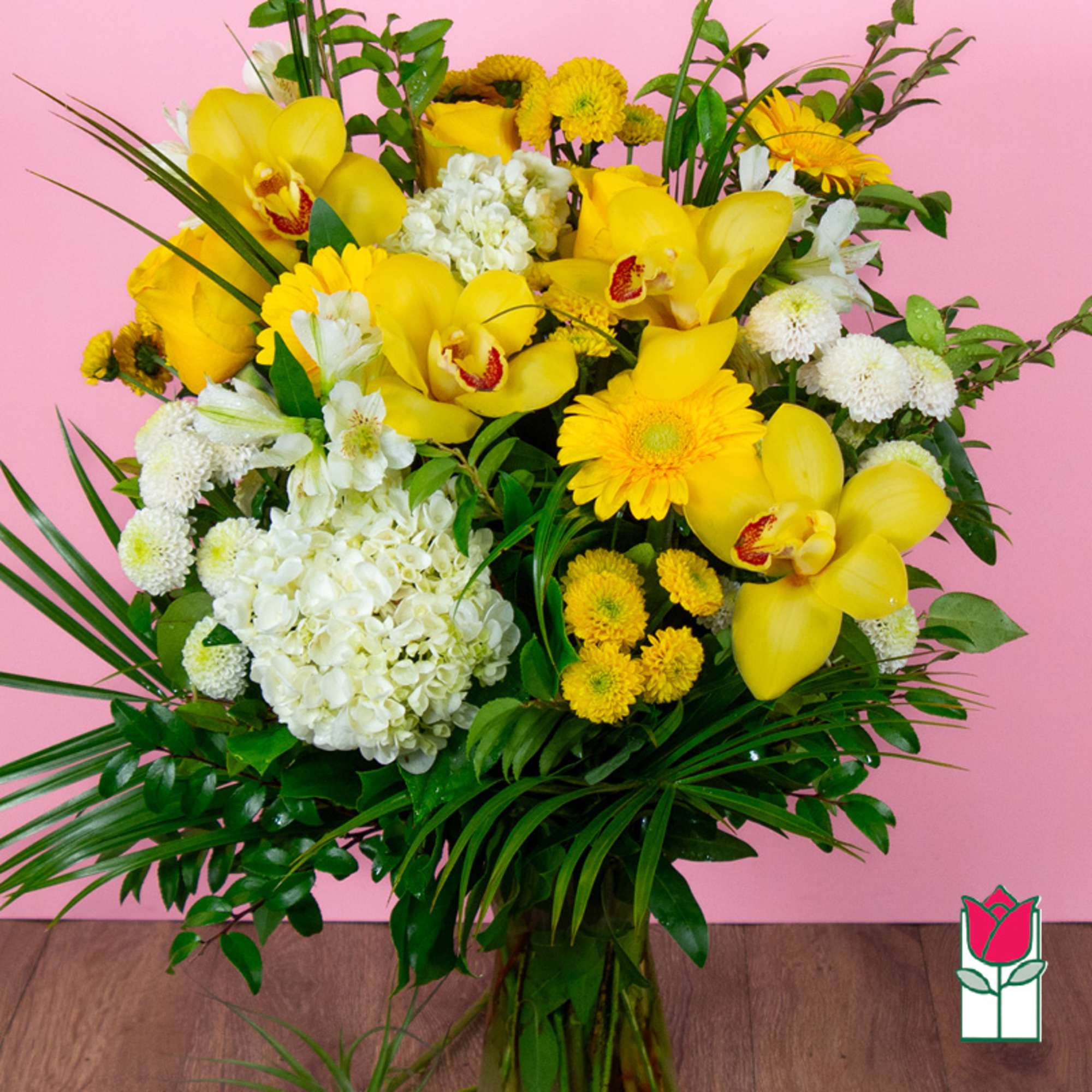 Yellow orchids and white flowers in a tall bouquet against a pink background