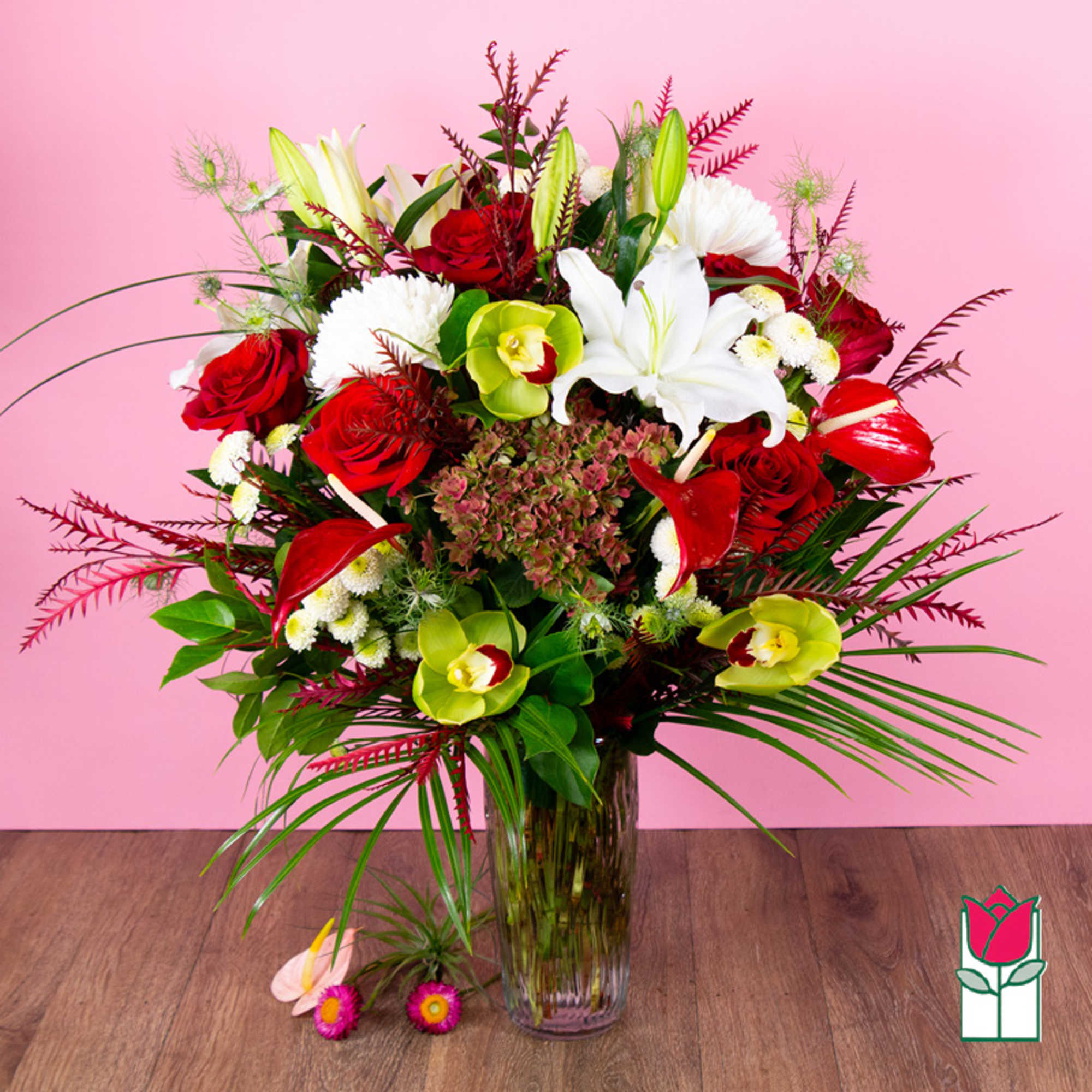 Mixed bouquet of red roses, white lilies, and green orchids in a glass vase