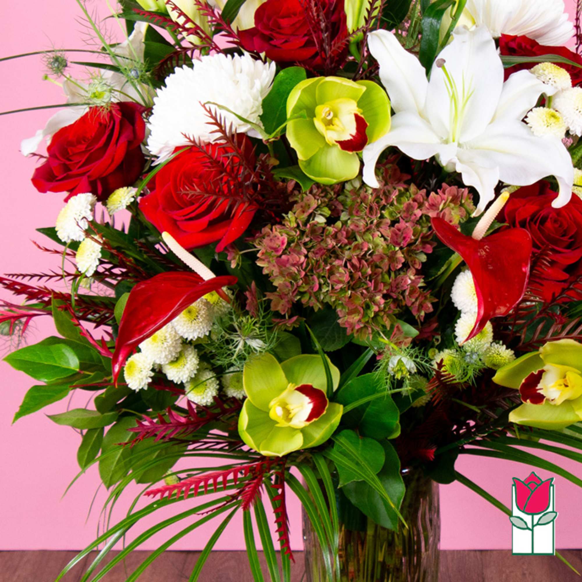 Bouquet of red roses, white lilies, and green orchids in a glass vase