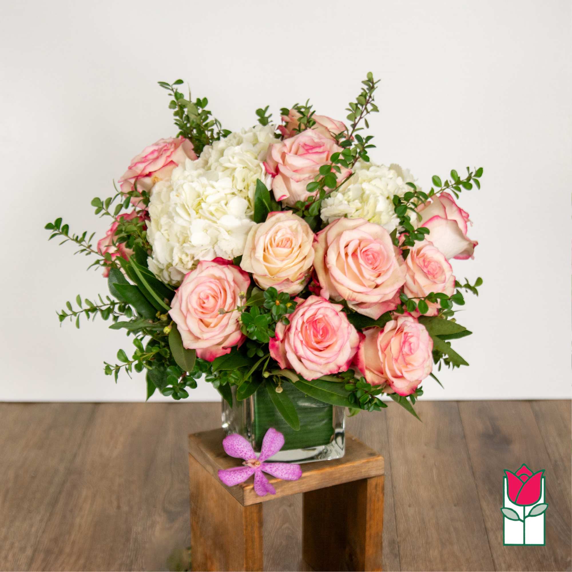 Pink roses and white hydrangeas in a clear glass vase.