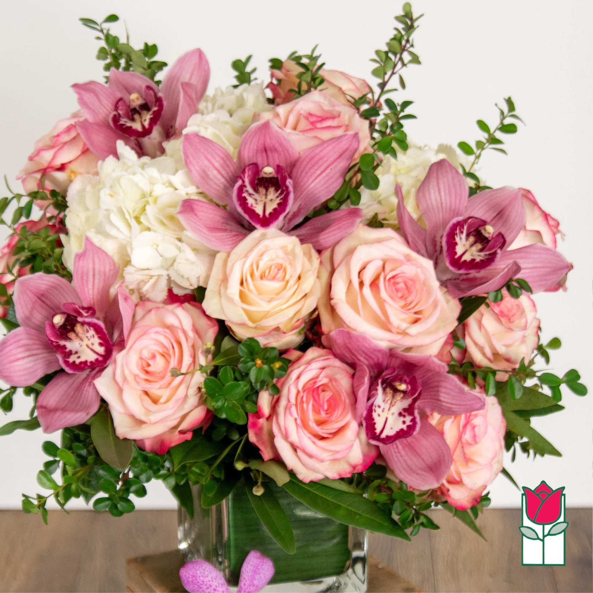 Pink roses and orchids arranged in a clear glass vase