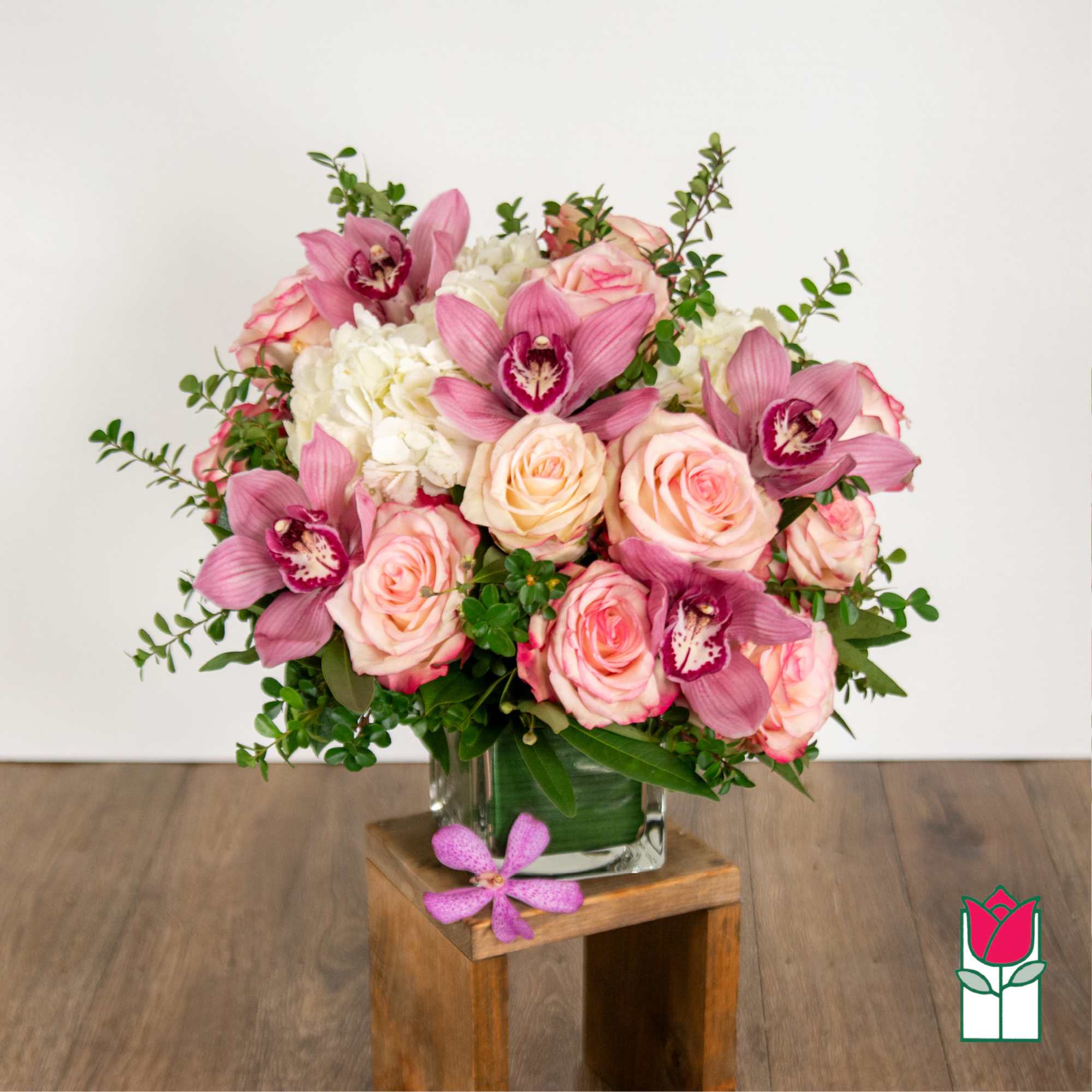 Pink roses and orchids arranged in a glass vase