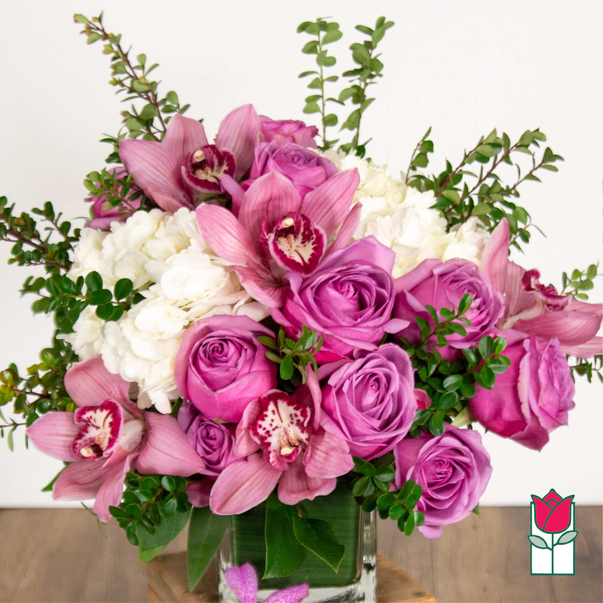 Pink roses and orchids arranged in a clear glass vase