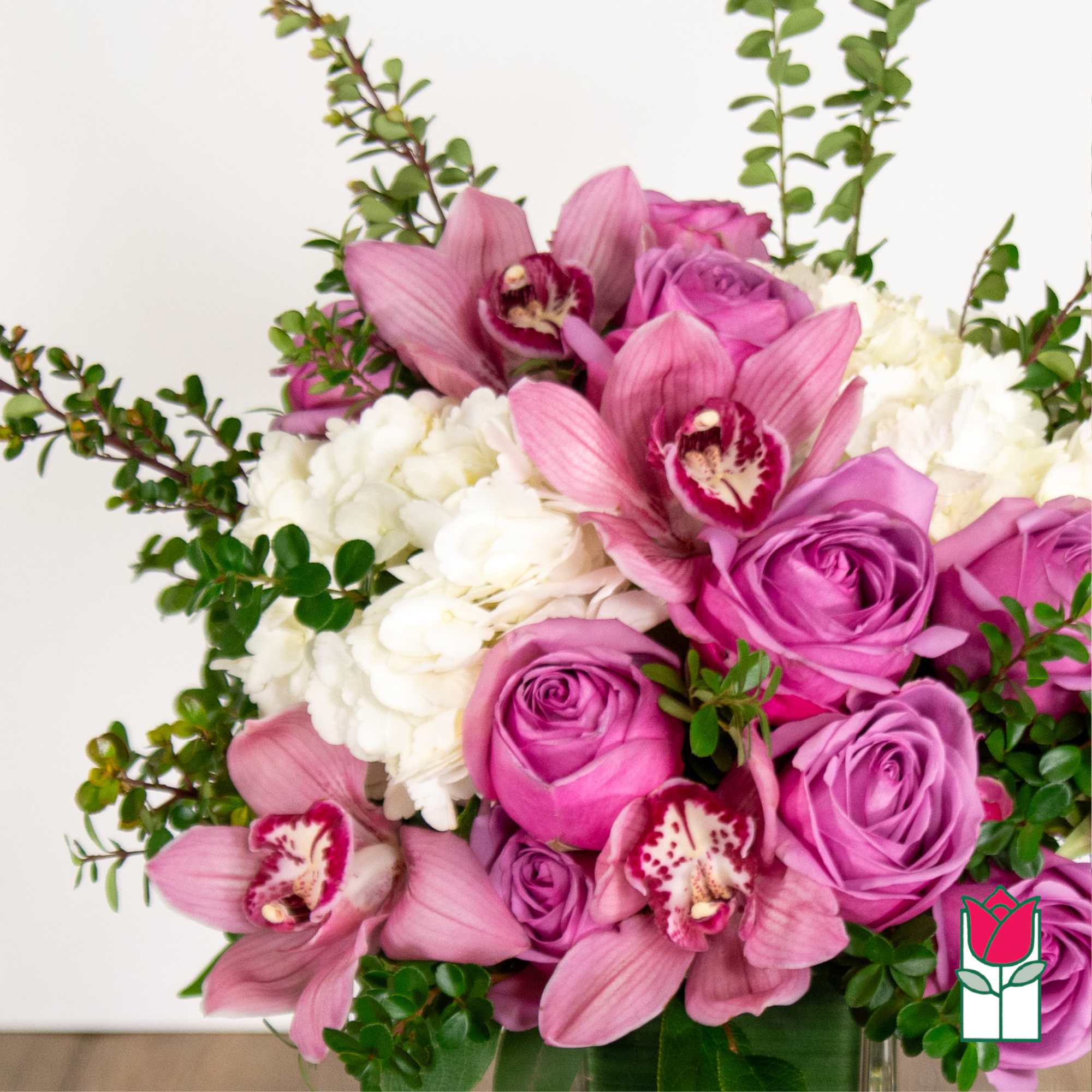 Pink roses and orchids arranged with white blooms in a vase