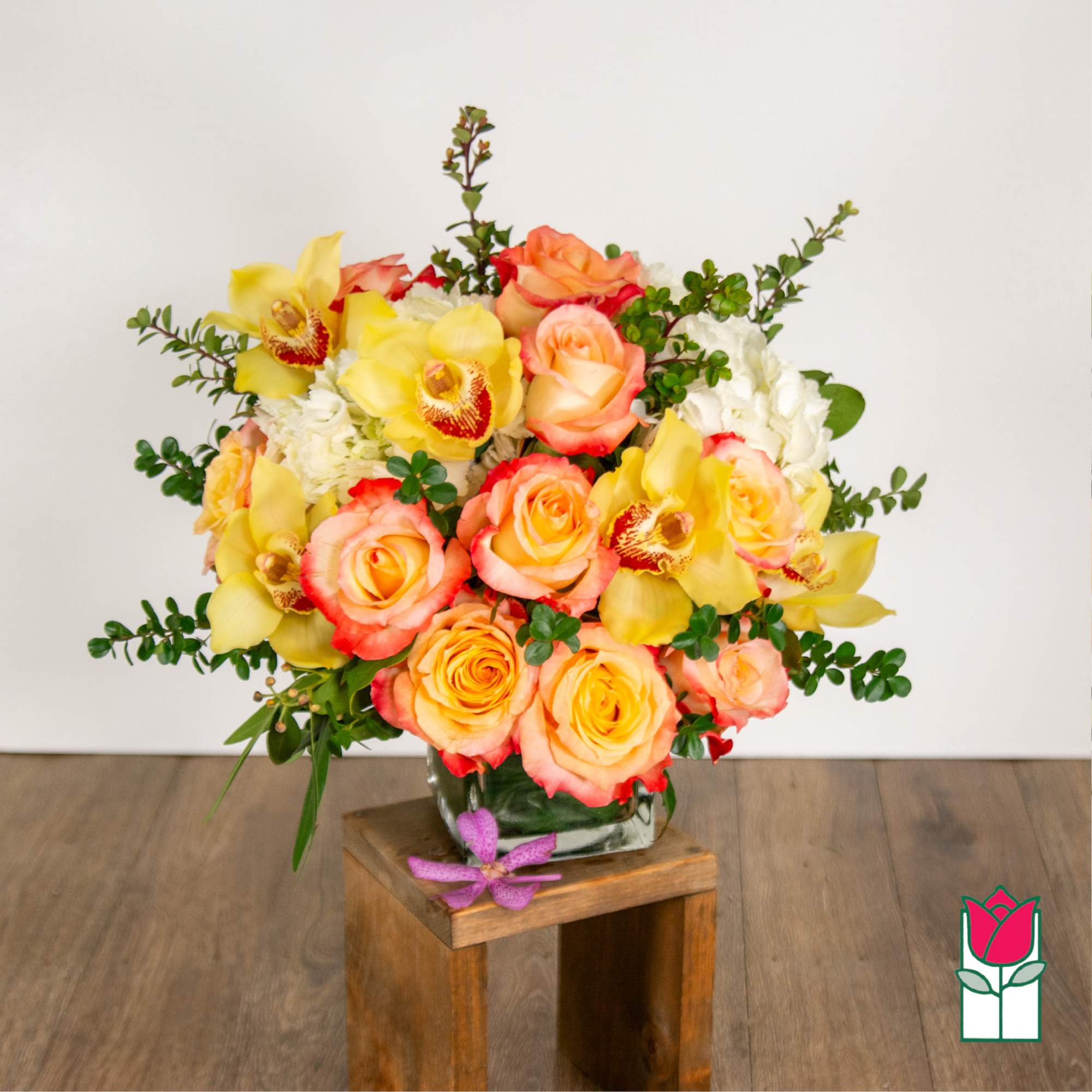 Bouquet of yellow orchids and peach roses in a glass vase