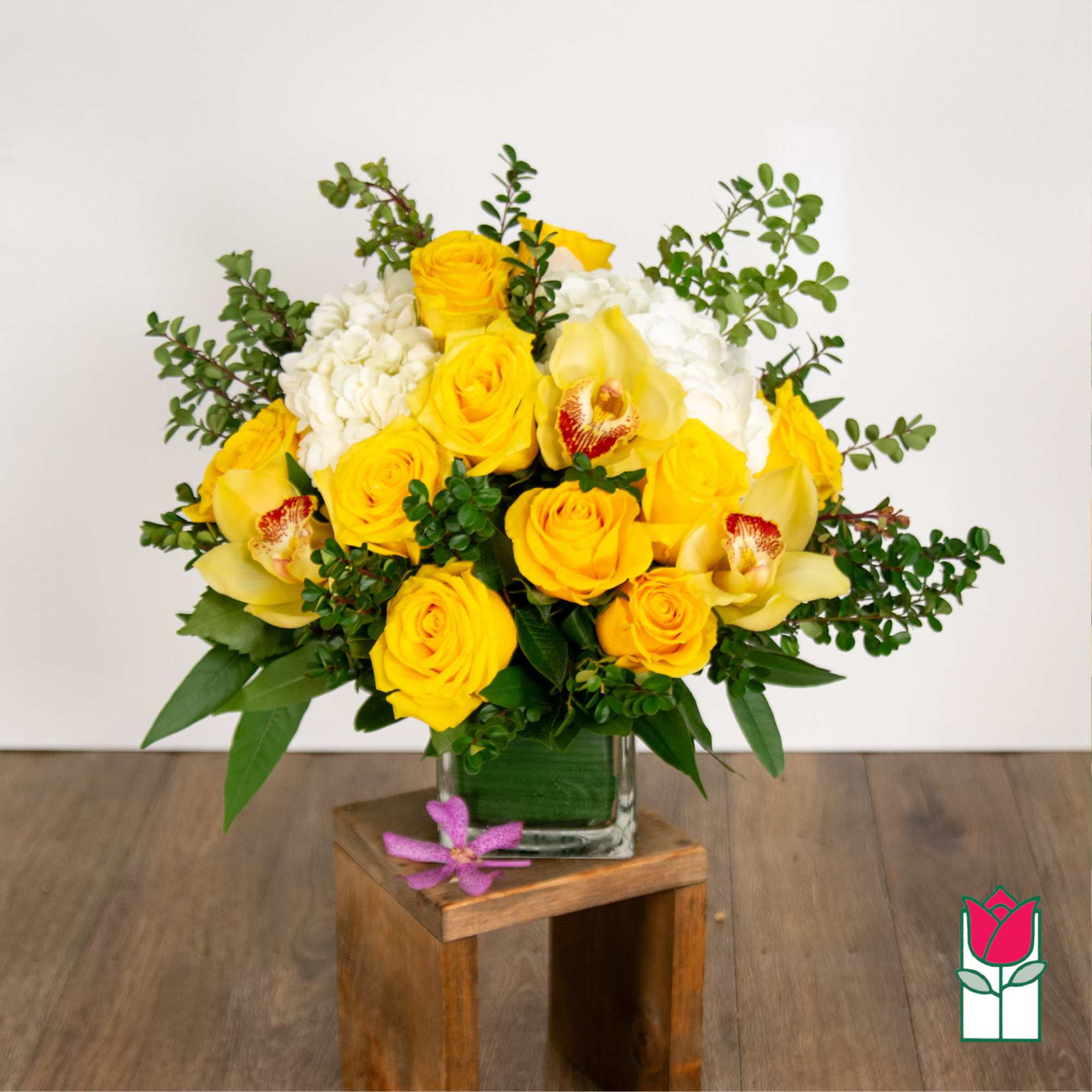 Yellow roses and white orchids arranged in a glass vase.