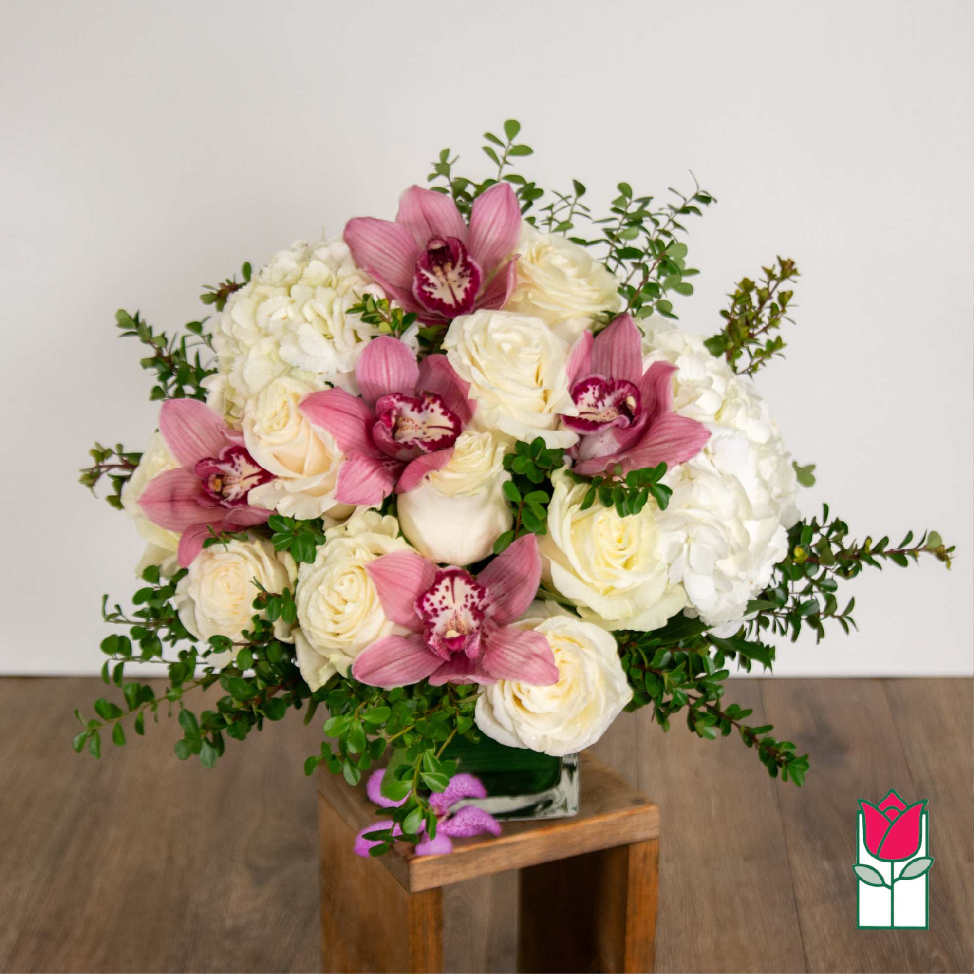 White roses and hydrangeas with pink orchids in a glass vase