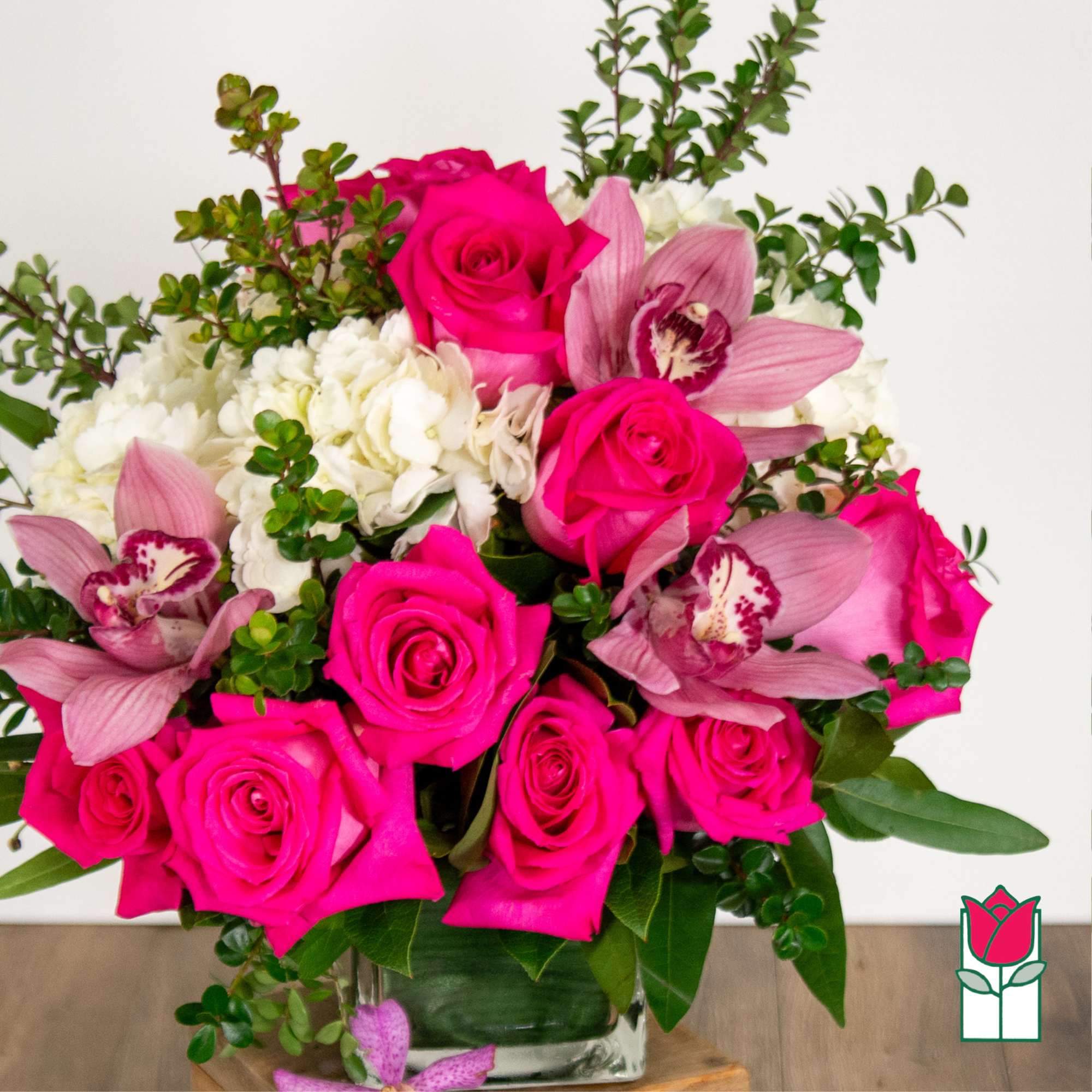 Pink roses and orchids arranged in a clear glass vase