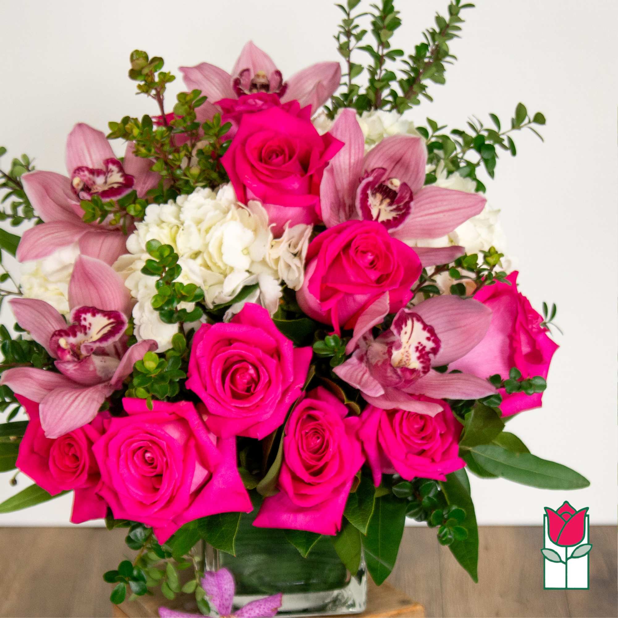 Pink roses and orchids arranged in a clear glass vase