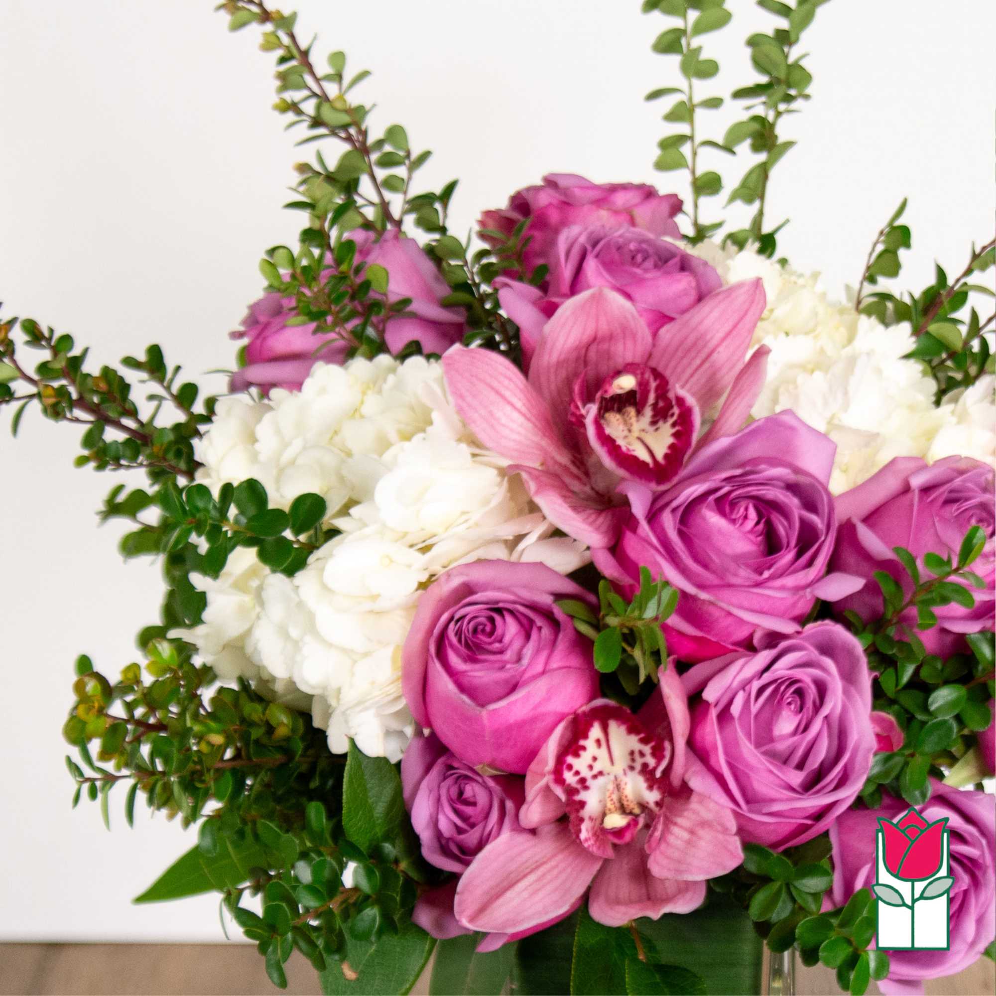 Pink roses and orchids arranged with white hydrangeas in a vase