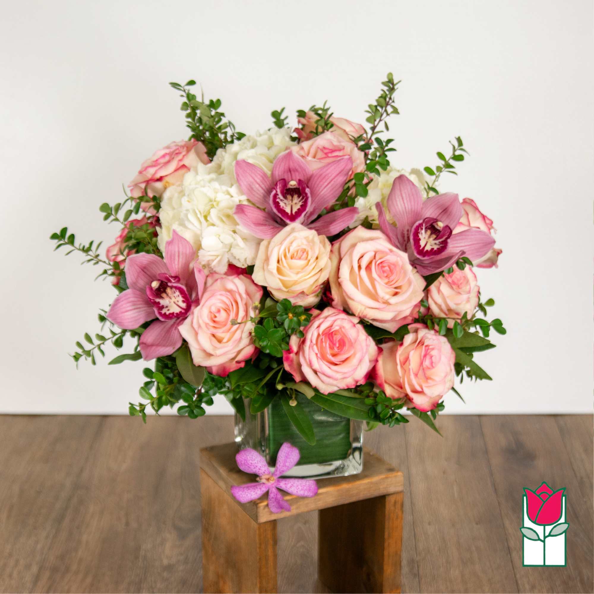 Pink roses and orchids arranged in a clear glass vase