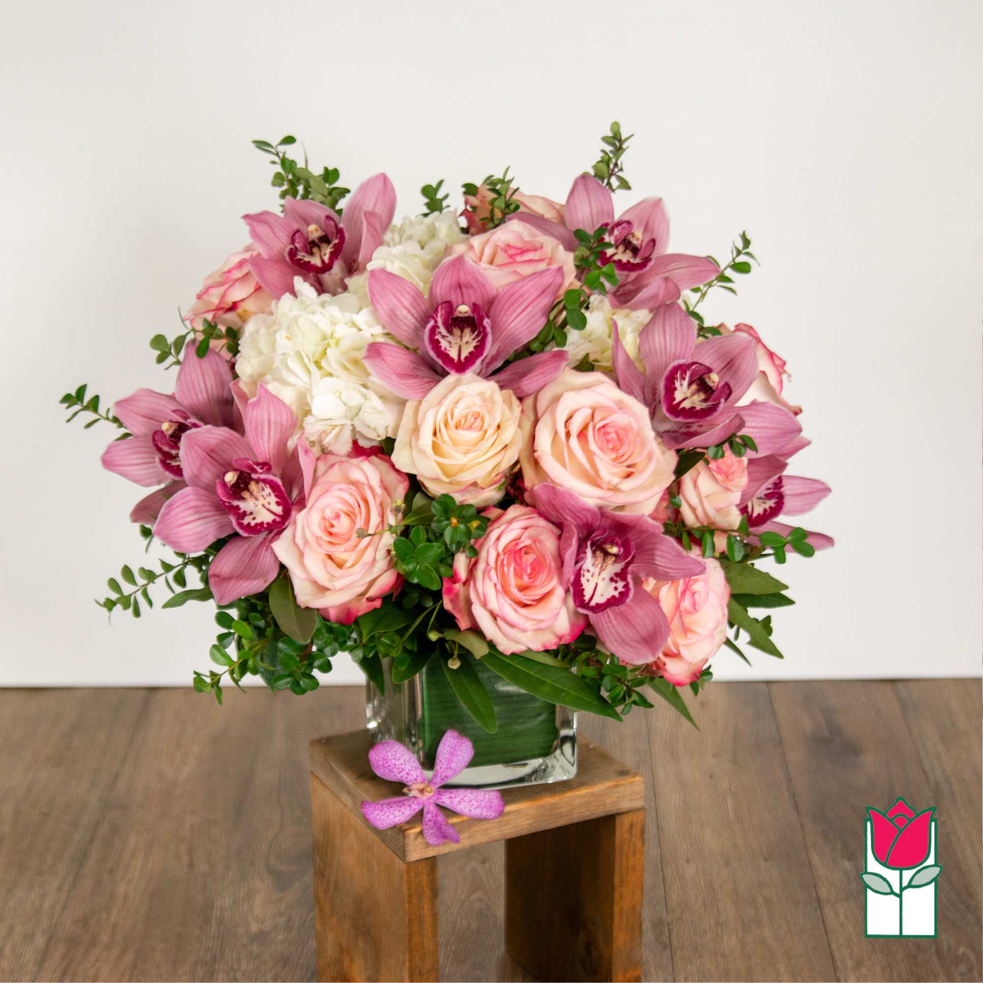 Pink roses and orchids arranged in a glass vase